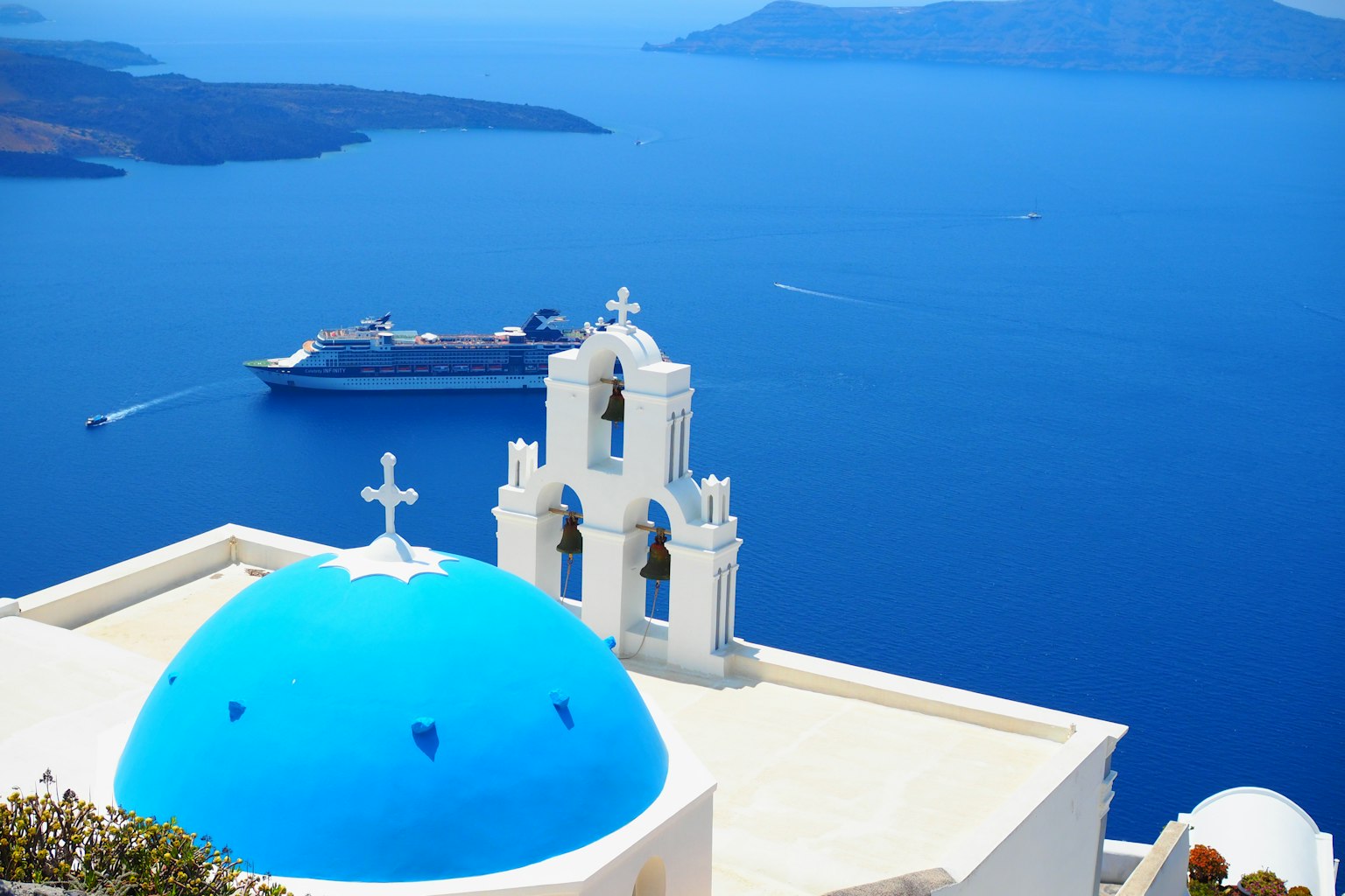 Pemandangan Santorini dengan gereja kubah biru dan kapal pesiar di latar belakang