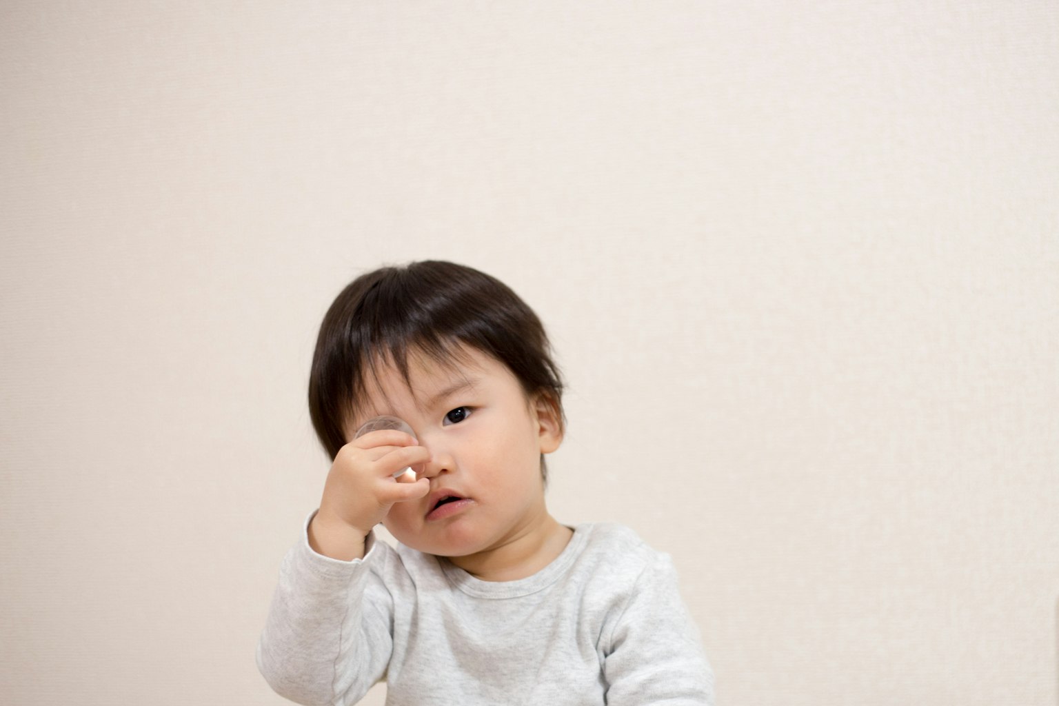 Seorang anak kecil mencubit hidungnya dengan ekspresi berpikir