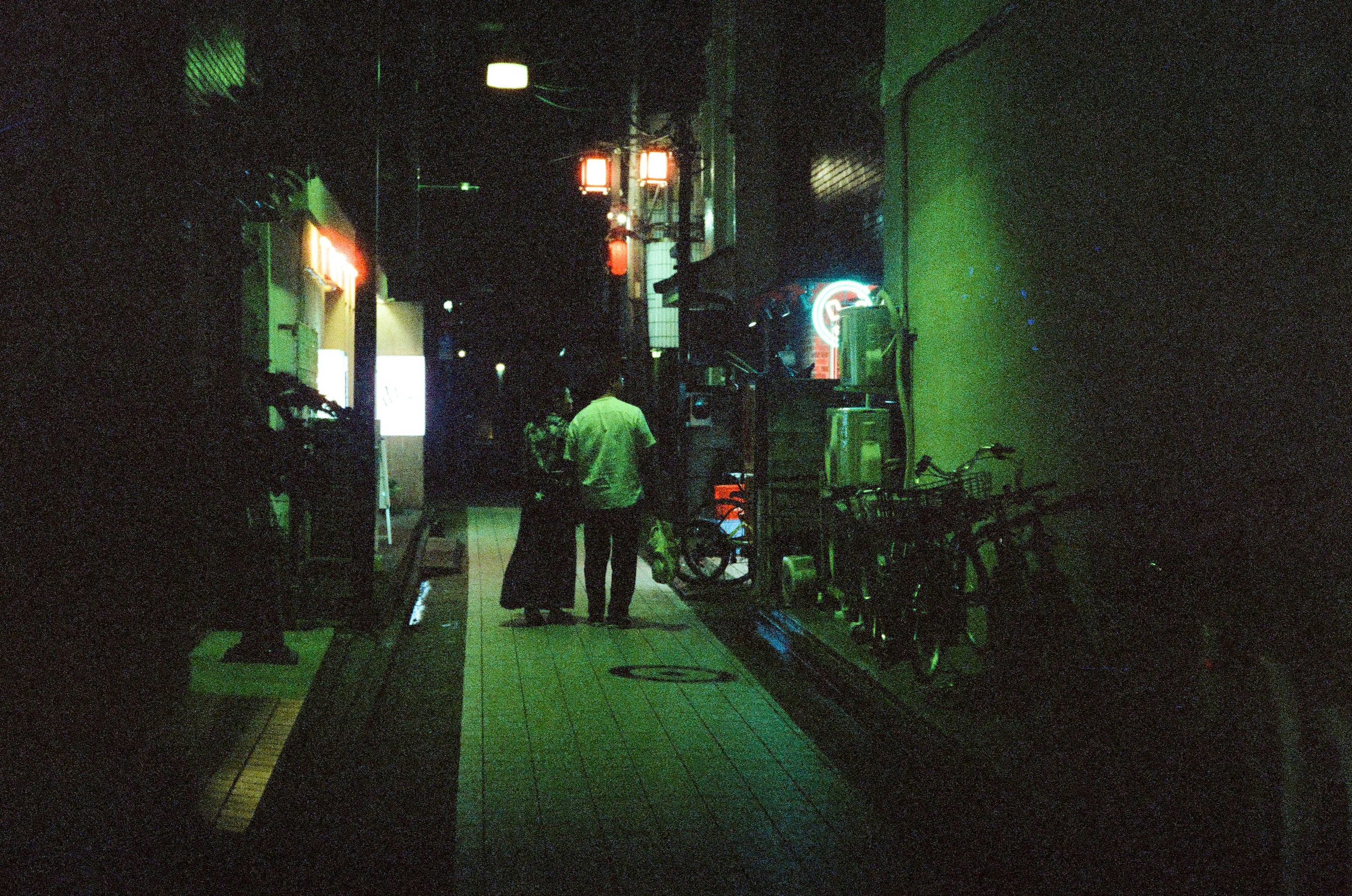 scène de ruelle nocturne avec enseignes lumineuses et silhouettes