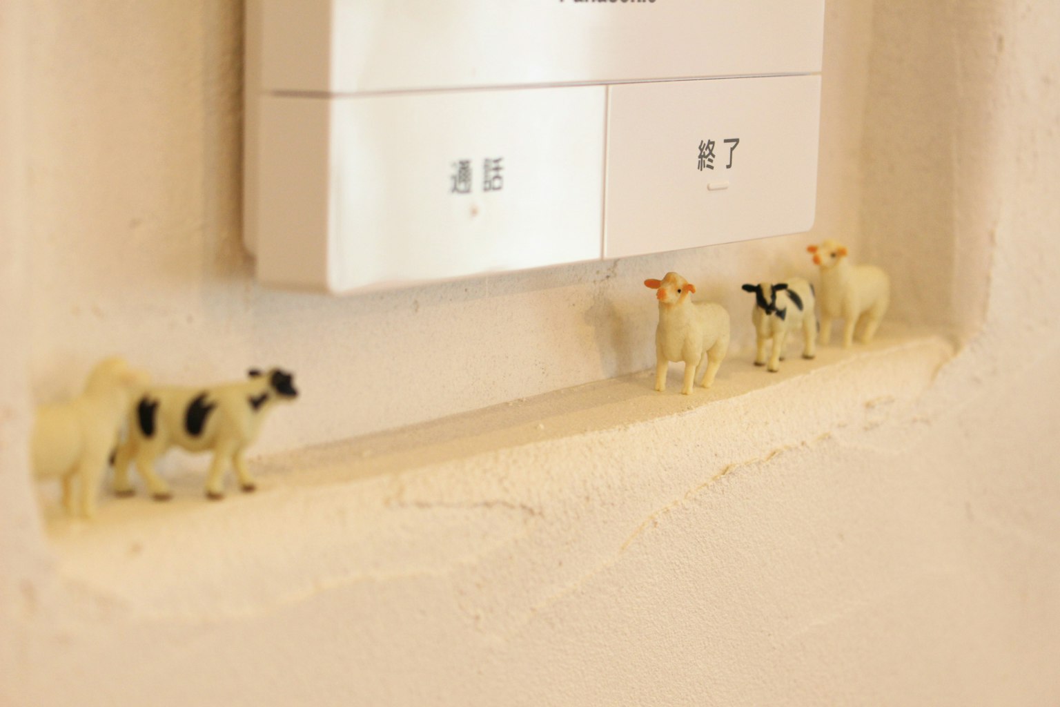 Những figurine bò nhỏ xếp hàng gần công tắc điện trên tường