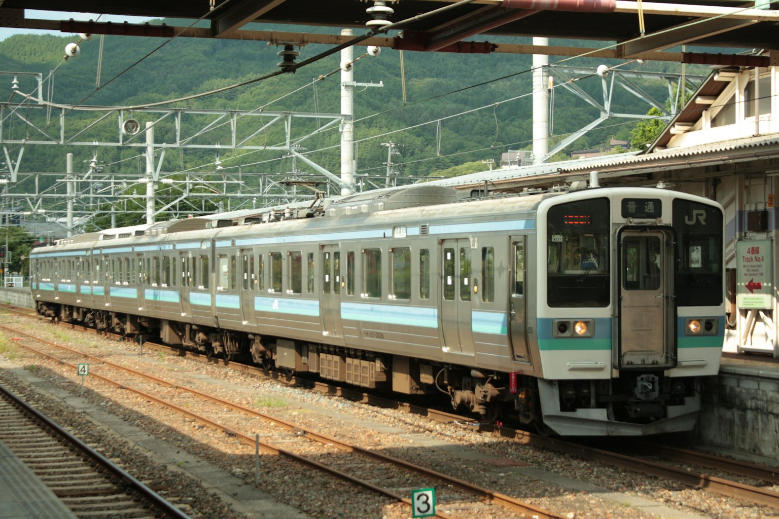 Un train bleu et blanc est arrêté à une gare