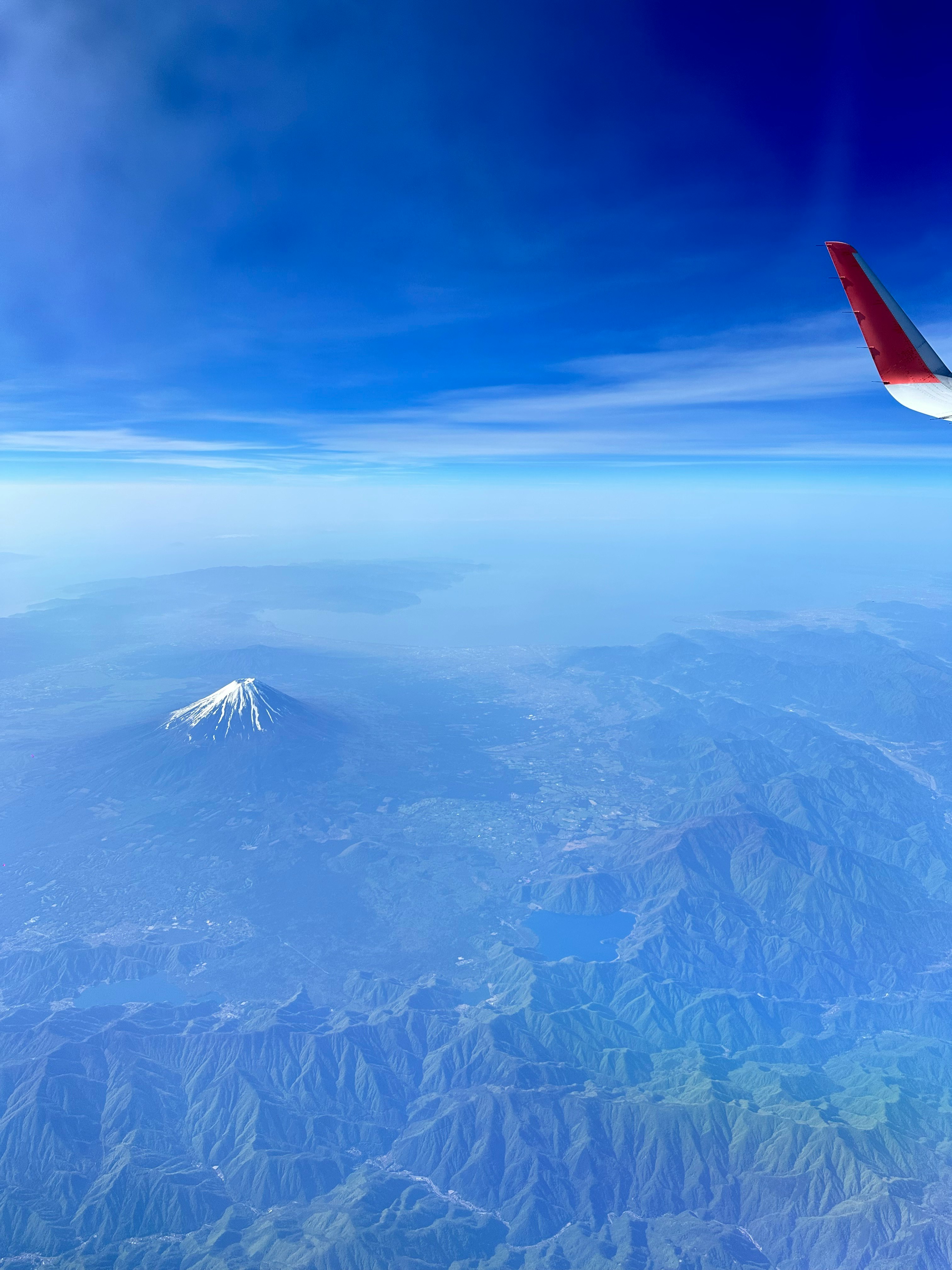 飛行機の窓から見える富士山と青い空の雲海