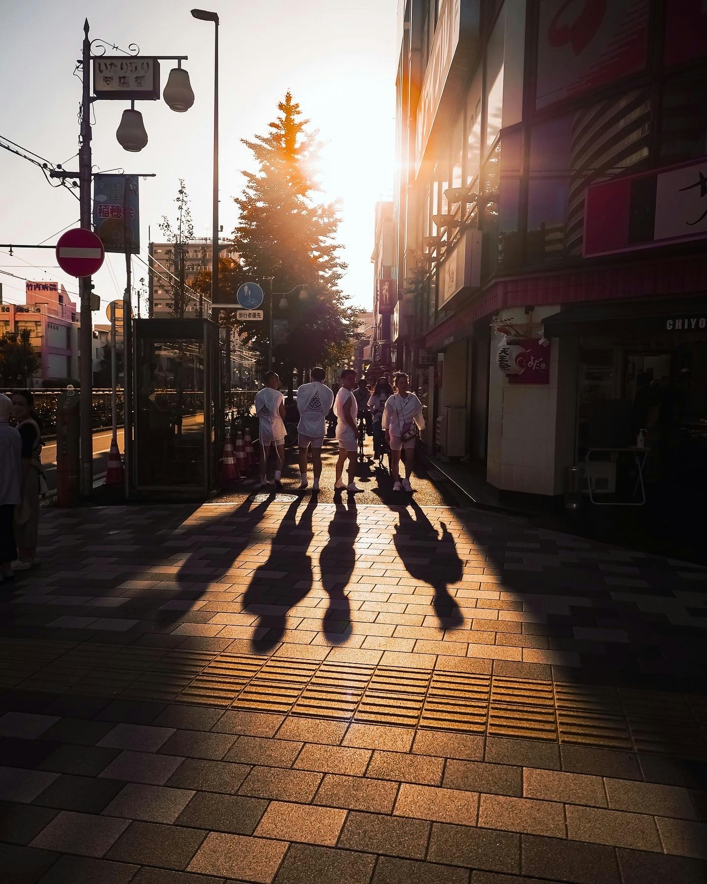 Silhouettes de personnes marchant dans une ruelle commerçante à la lumière du coucher du soleil