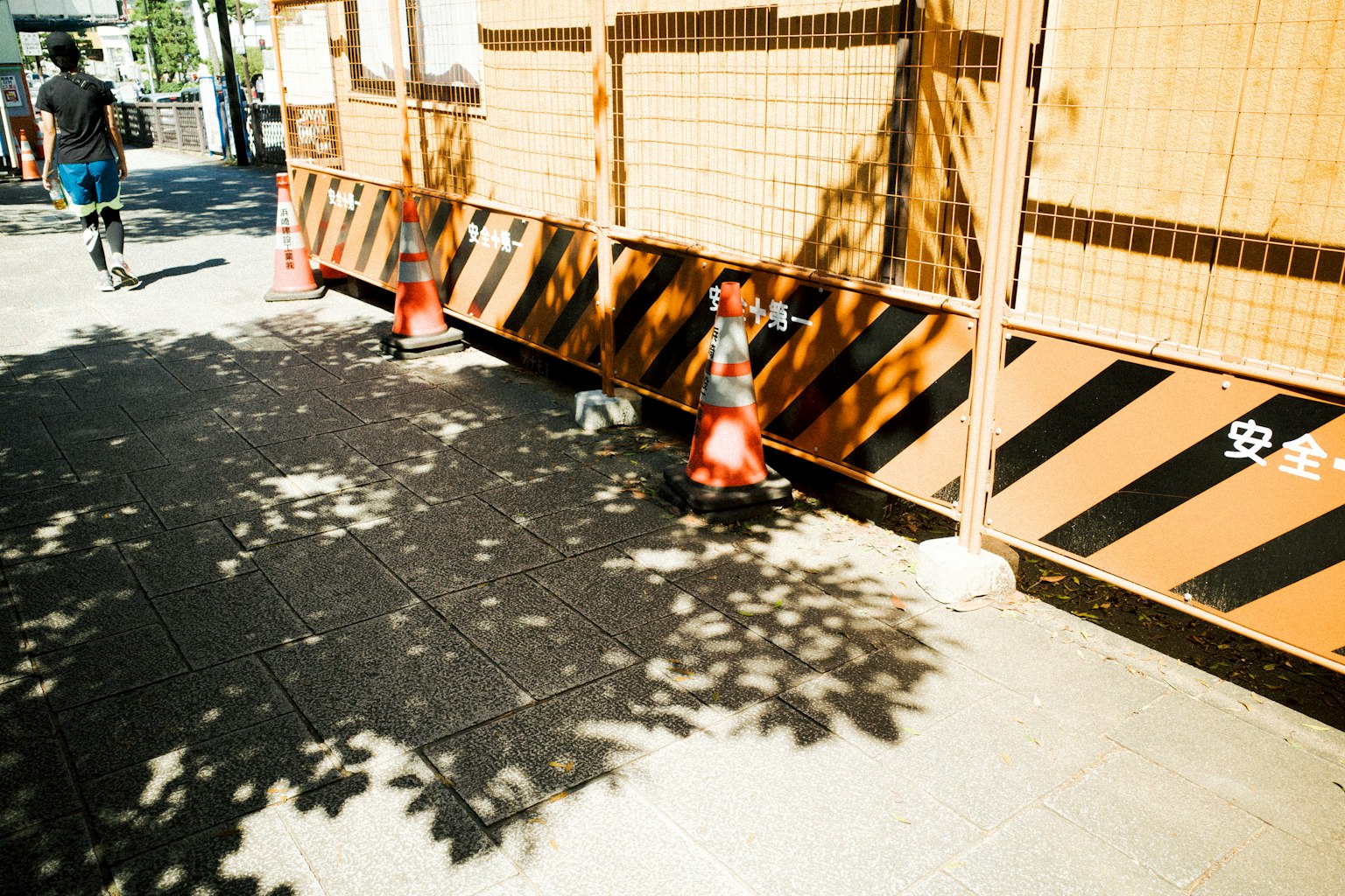 人行道上的施工锥体和阴影，以及条纹路障