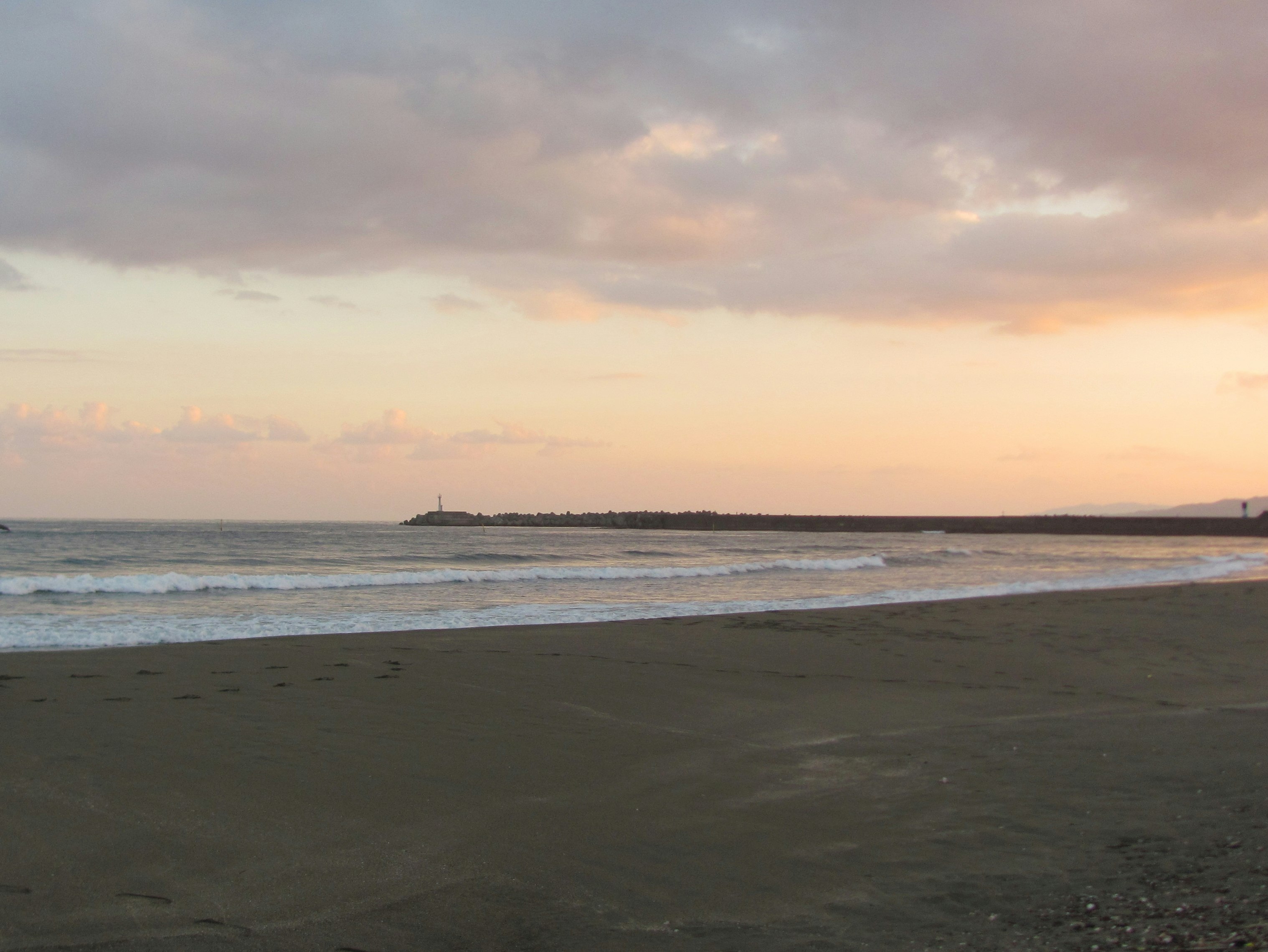 夕焼けの海辺に続く砂浜と波