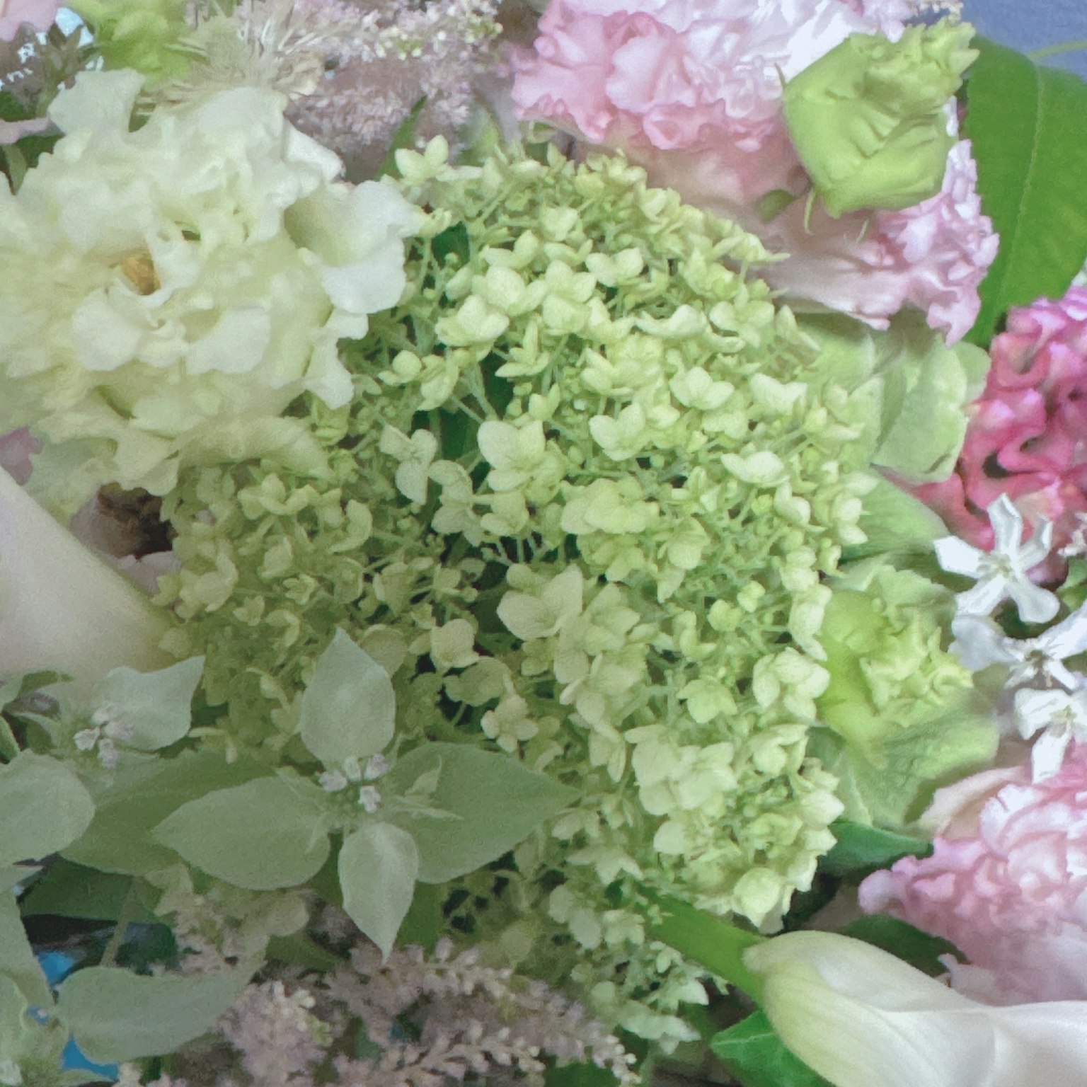 Un arrangement floreale con fiori dai colori tenui tra cui ortensie e gigli