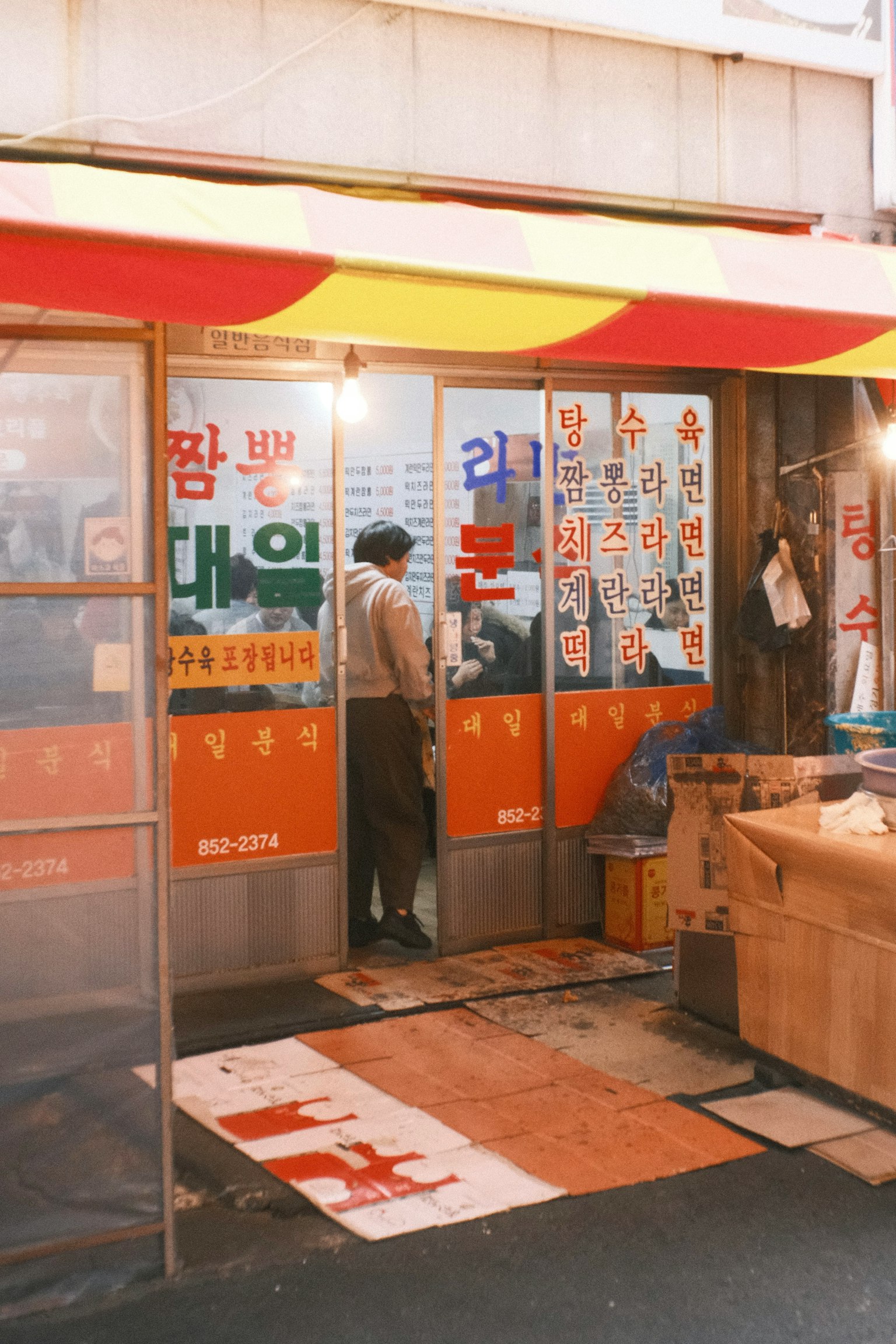 韩国商店的外观有色彩鲜艳的招牌一个男人站在门前