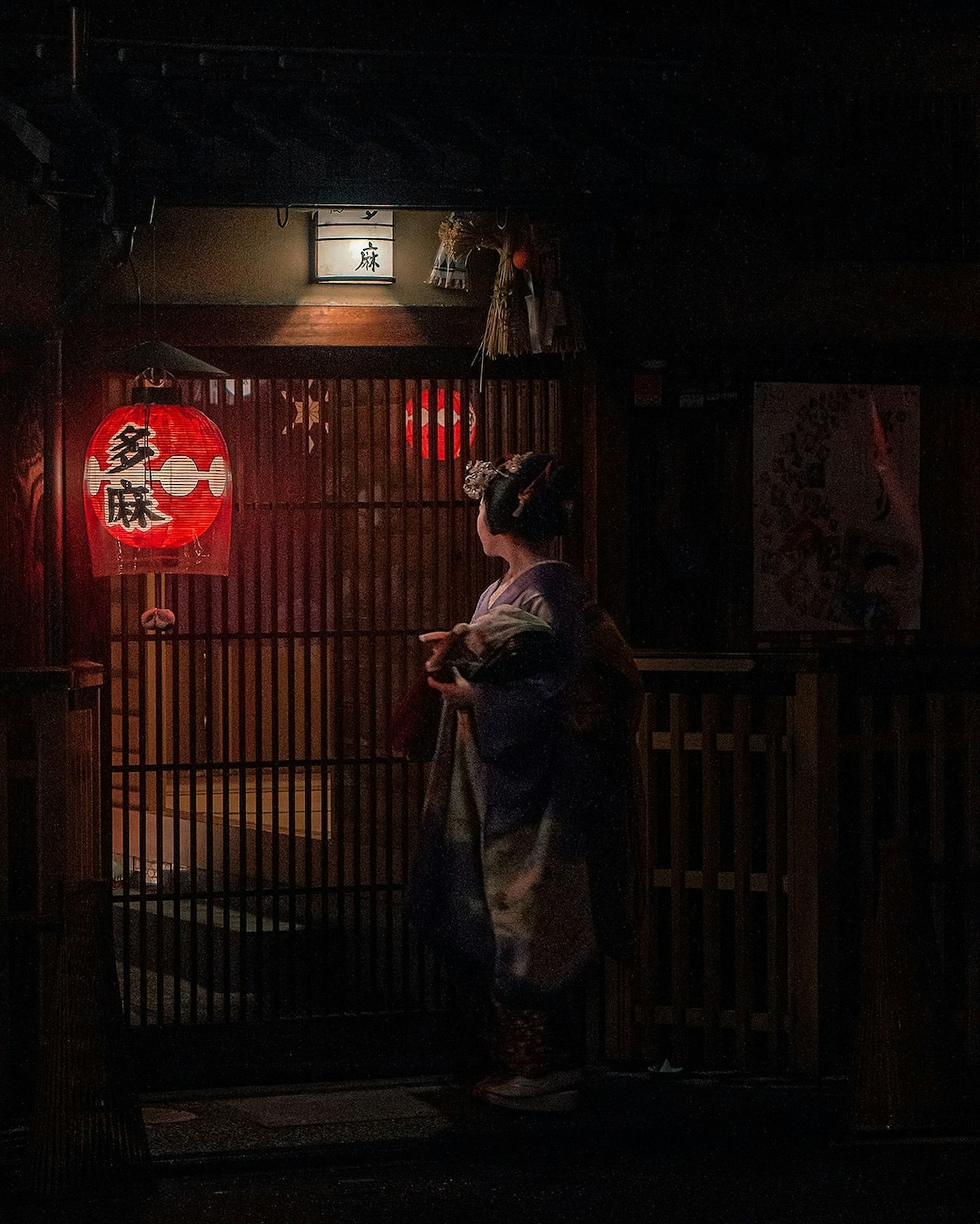 穿着和服的女性站在有红色灯笼的传统日本入口前