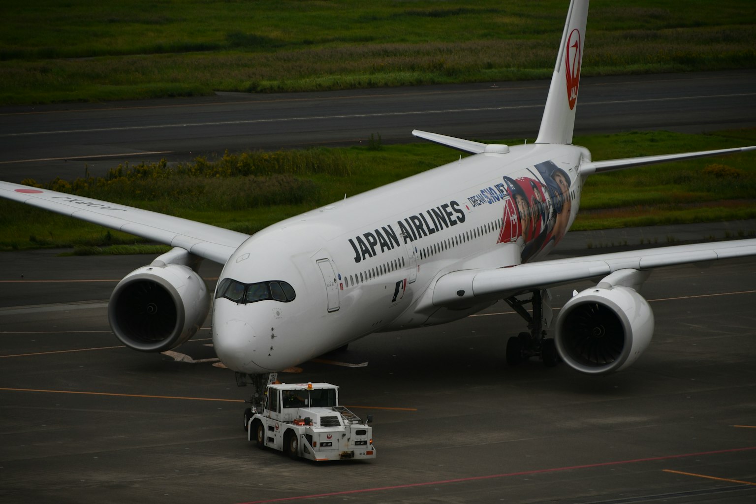 Boeing 787 de Japan Airlines siendo remolcado por un tractor en la pista