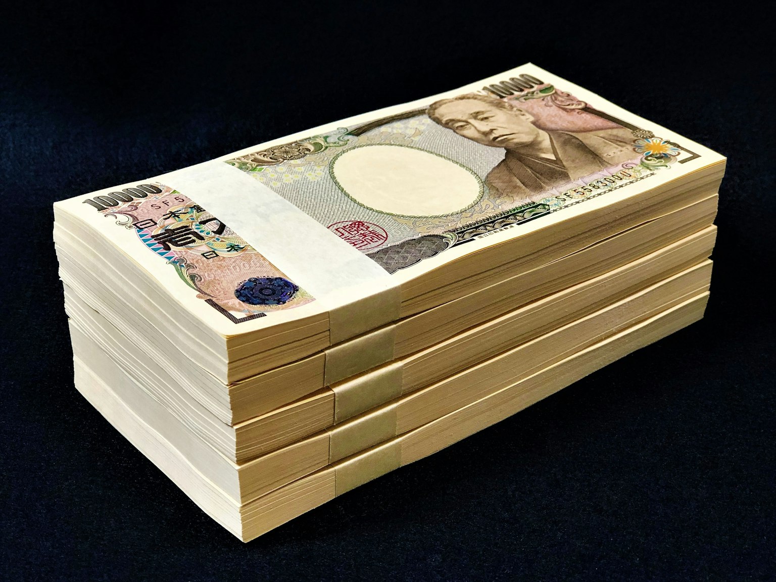 一堆日本日元鈔票放在黑色背景上