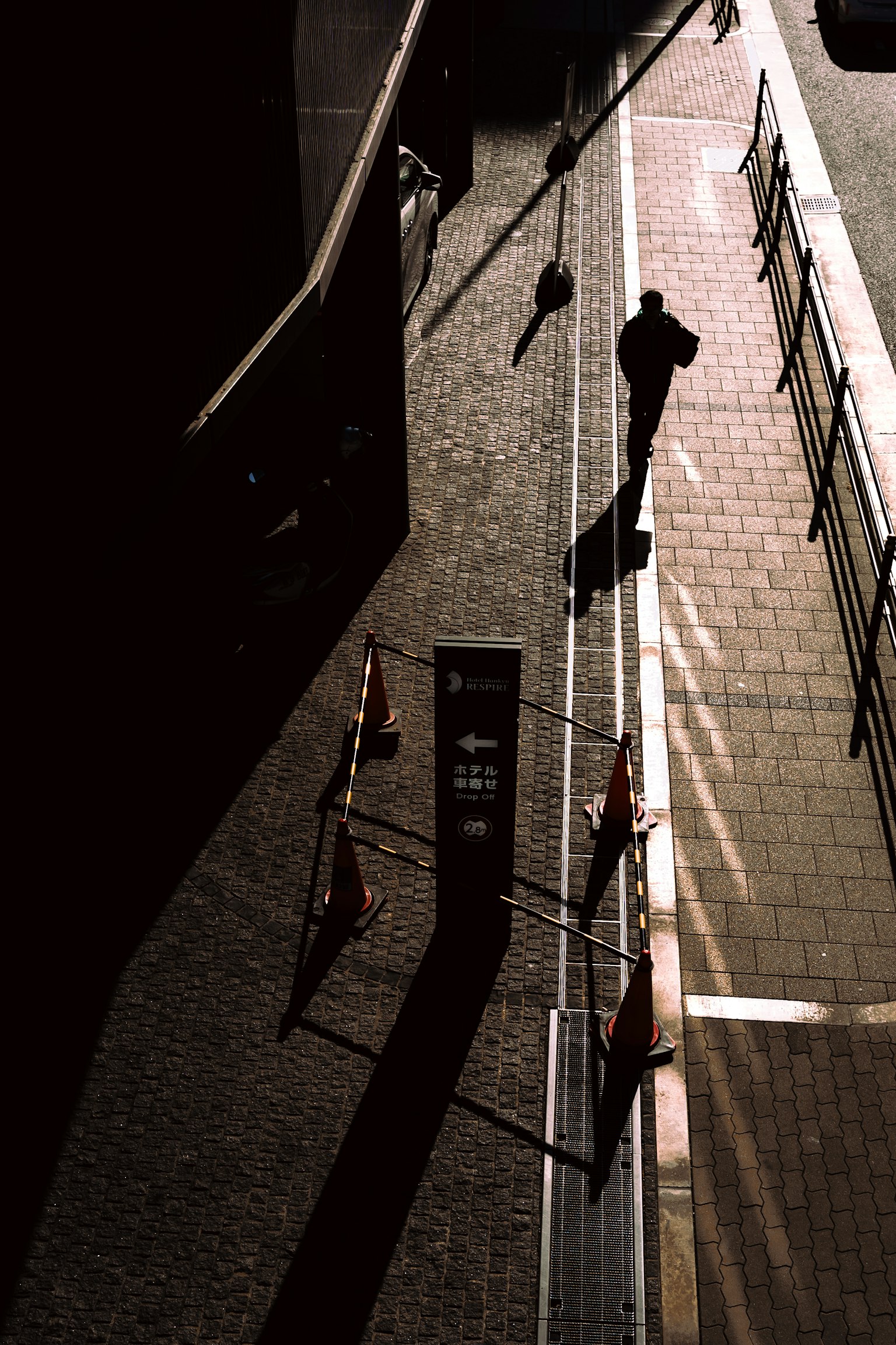 Silhouette d'une personne marchant dans l'ombre sur une rue pavée