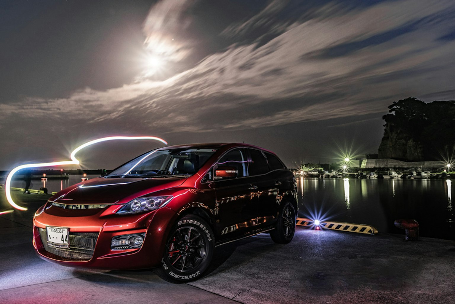 Roter SUV, der nachts am Hafen mit einem hellen Mond parkt