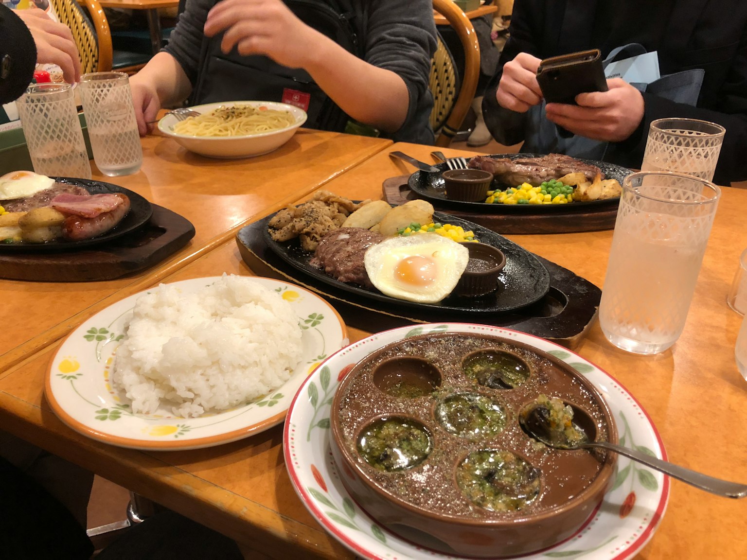 나무 테이블 위에 여러 요리와 배경의 사람 손