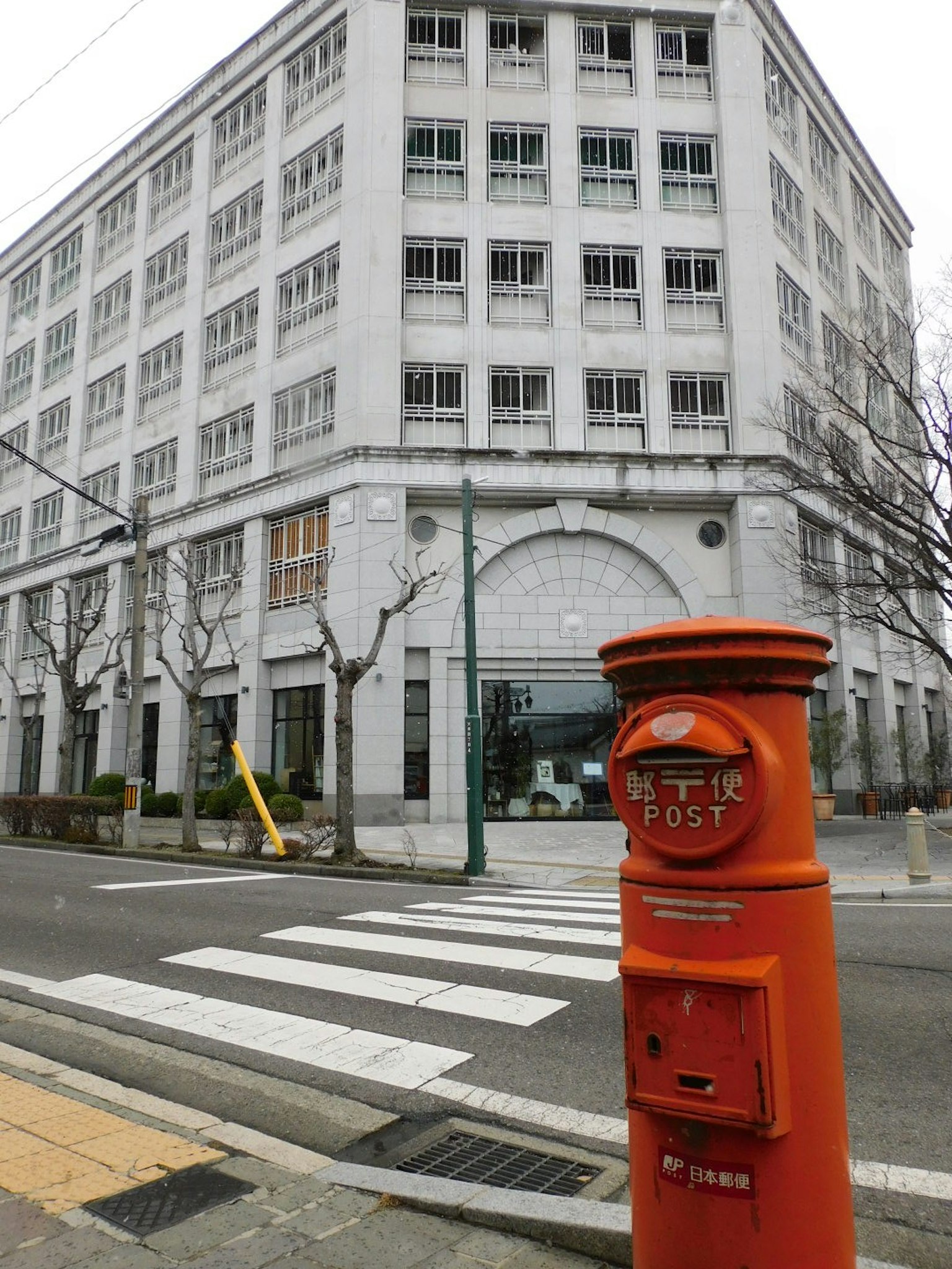 Orange mailbox next to a modern building on a street corner