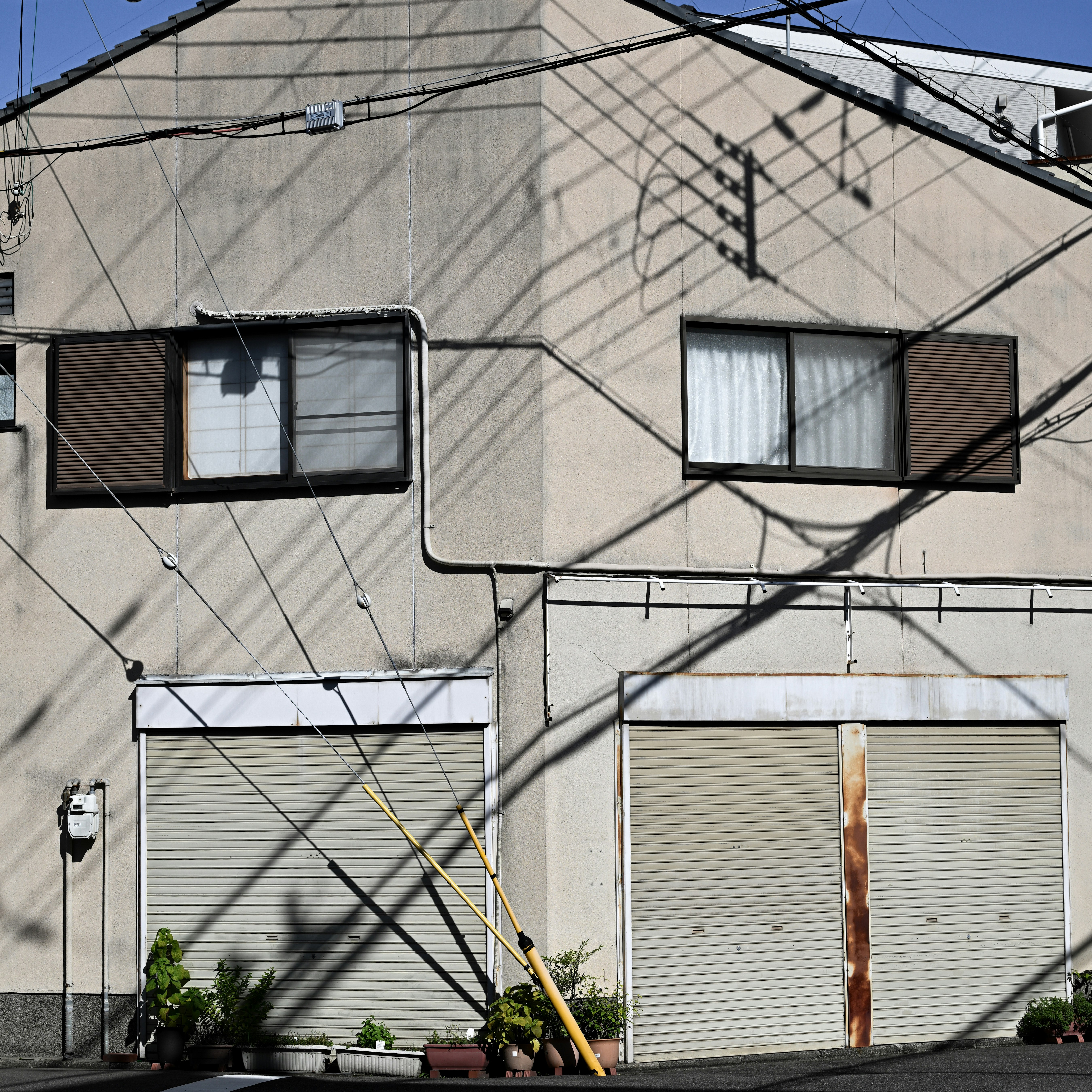 架線と壁に囲まれた二階建ての家の青空