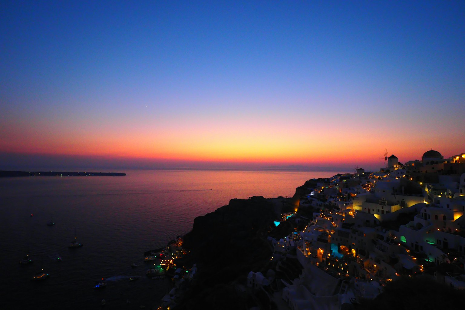 Magnifique coucher de soleil sur la mer avec des lumières sur l'île de Santorin