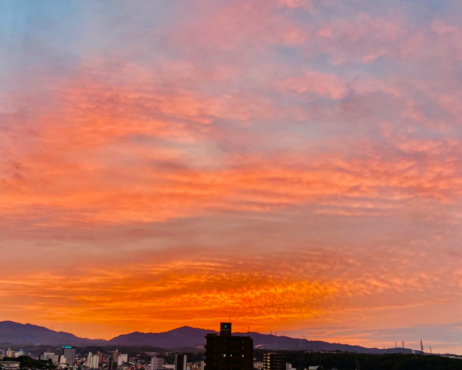 Meraviglioso cielo al tramonto con sfumature arancioni e rosa e silhouette di montagne