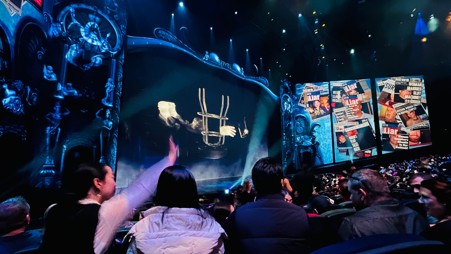 Pubblico che osserva uno spettacolo sul palco con illuminazione speciale e schermi digitali
