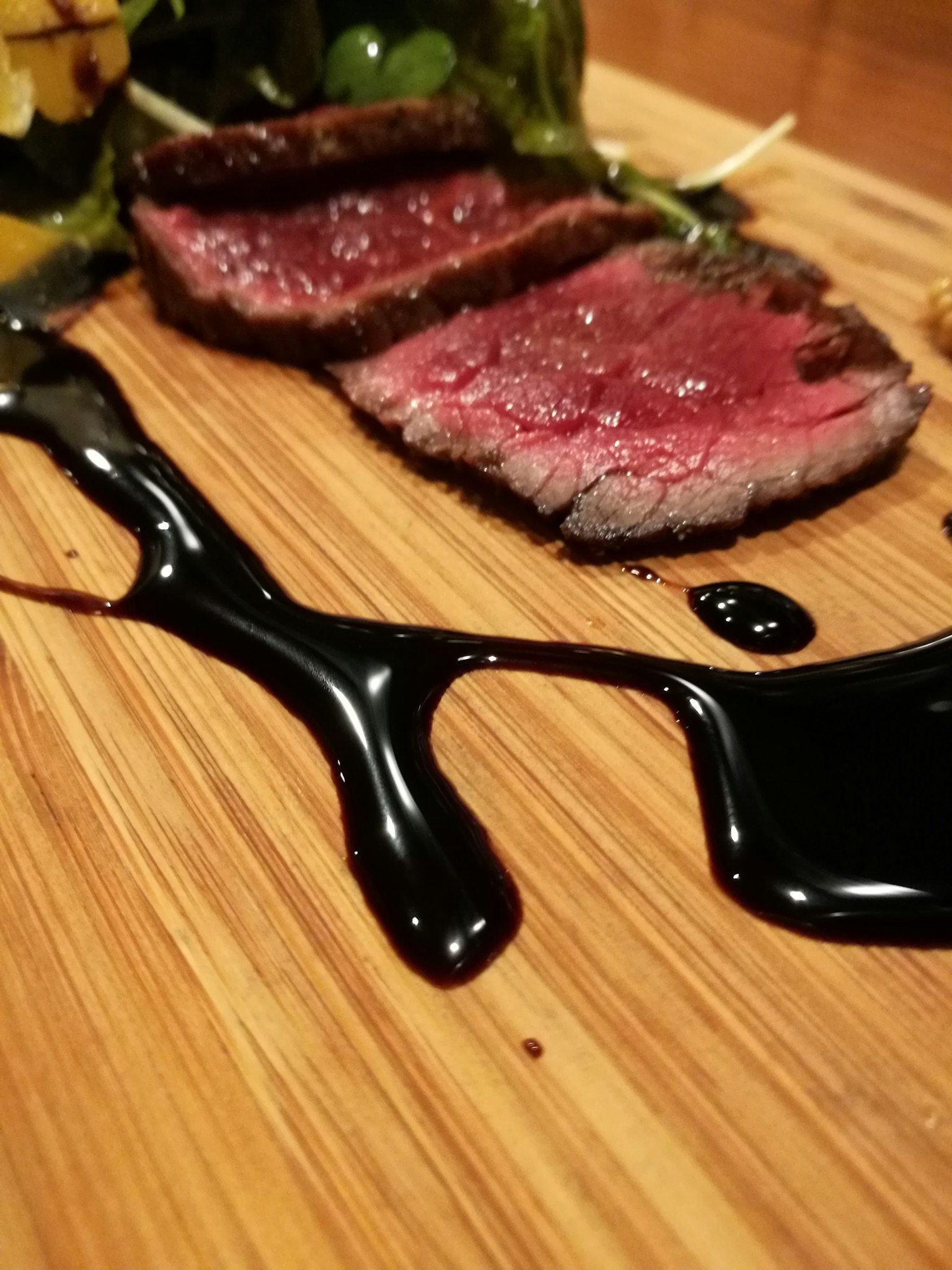 In Scheiben geschnittenes Fleisch auf einem Holzbrett mit dunkler Sauce