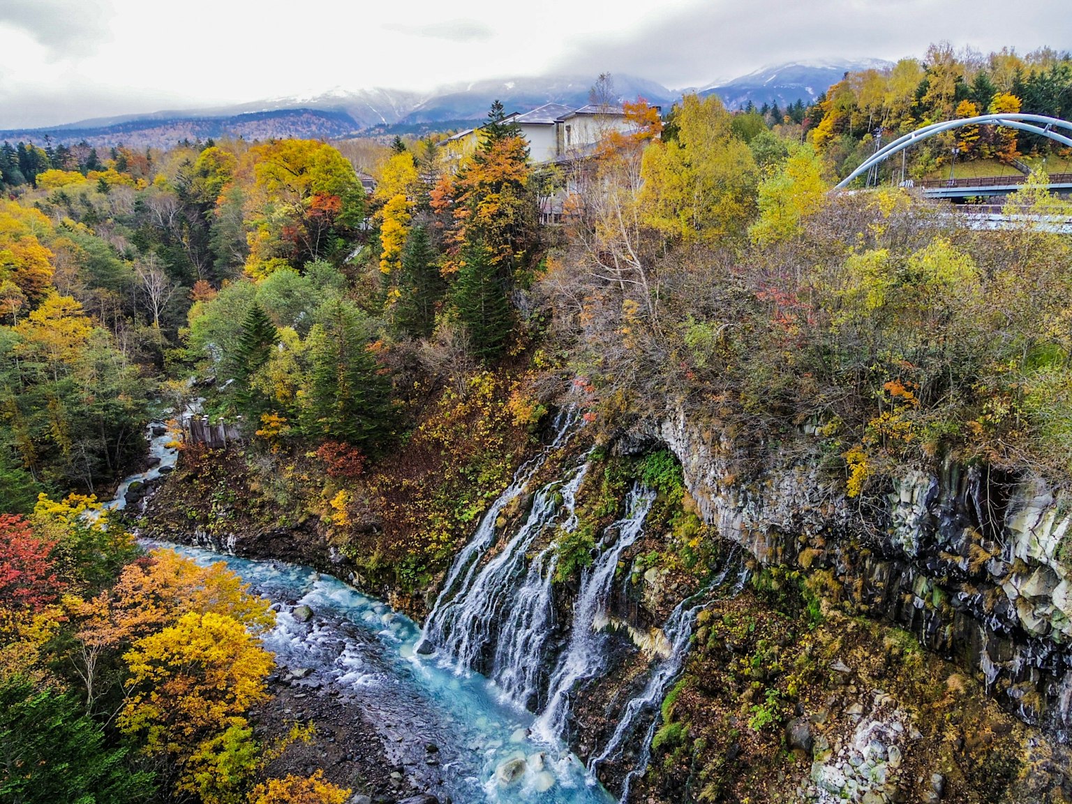 Vue pittoresque d'une cascade et d'une rivière entourée de feuillage d'automne avec des arbres verts et orange vibrants