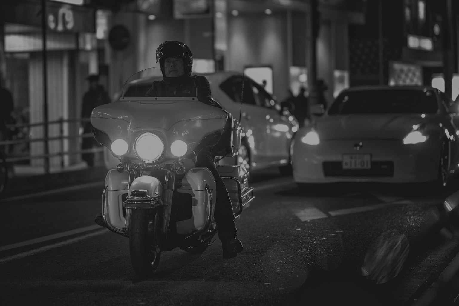 A motorcycle rider navigating through city traffic at night