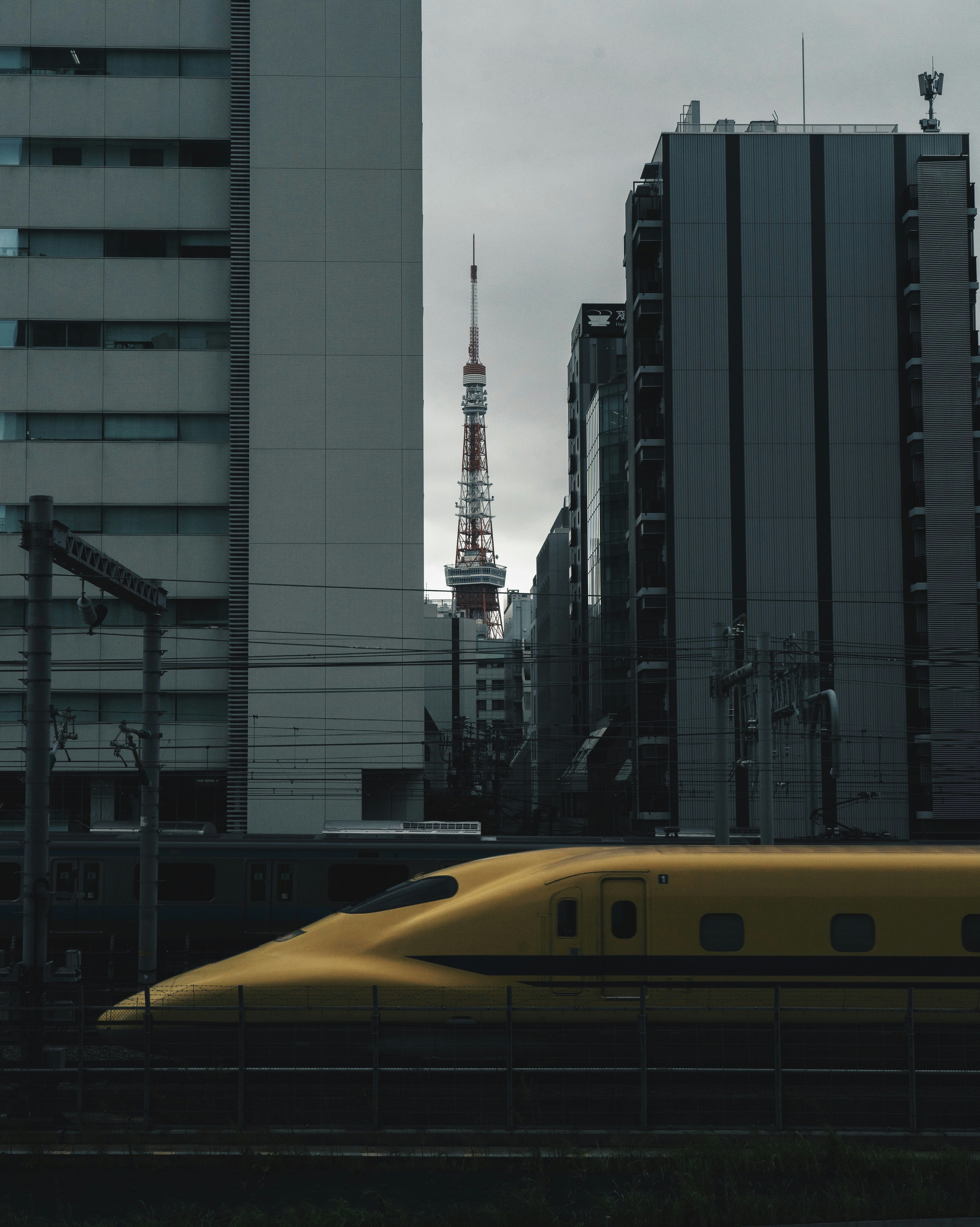 ビル群の間を走る新幹線と東京タワーのような電波塔のある都市風景