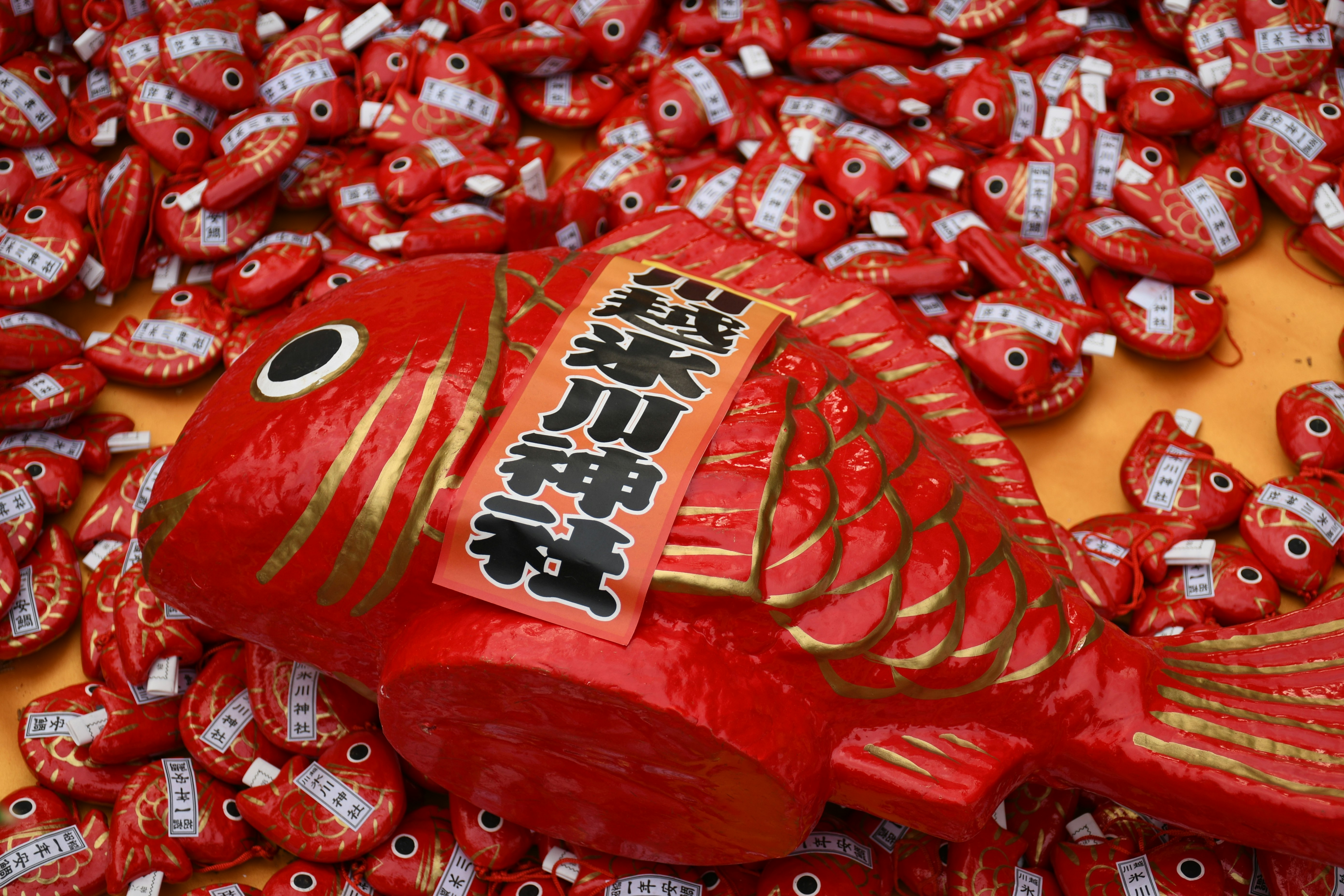 赤い鯛の置物と小さな縁起物が並ぶ縁日風の飾り画像