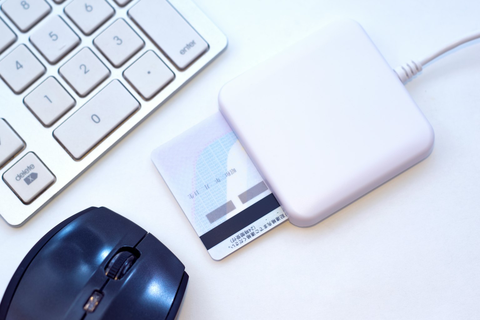 Image de bureau avec un lecteur de carte blanc et une carte de crédit placée dessus à côté d'une souris et d'un clavier