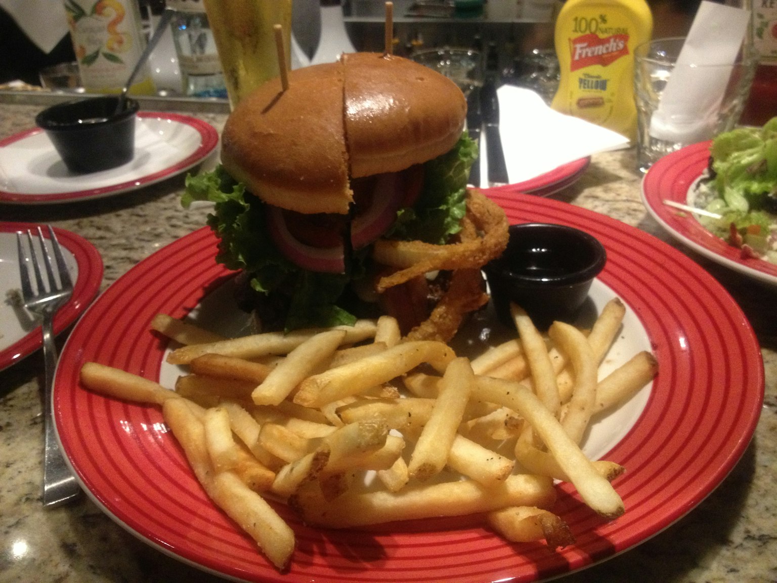 Hamburger delizioso con patatine su un piatto rosso