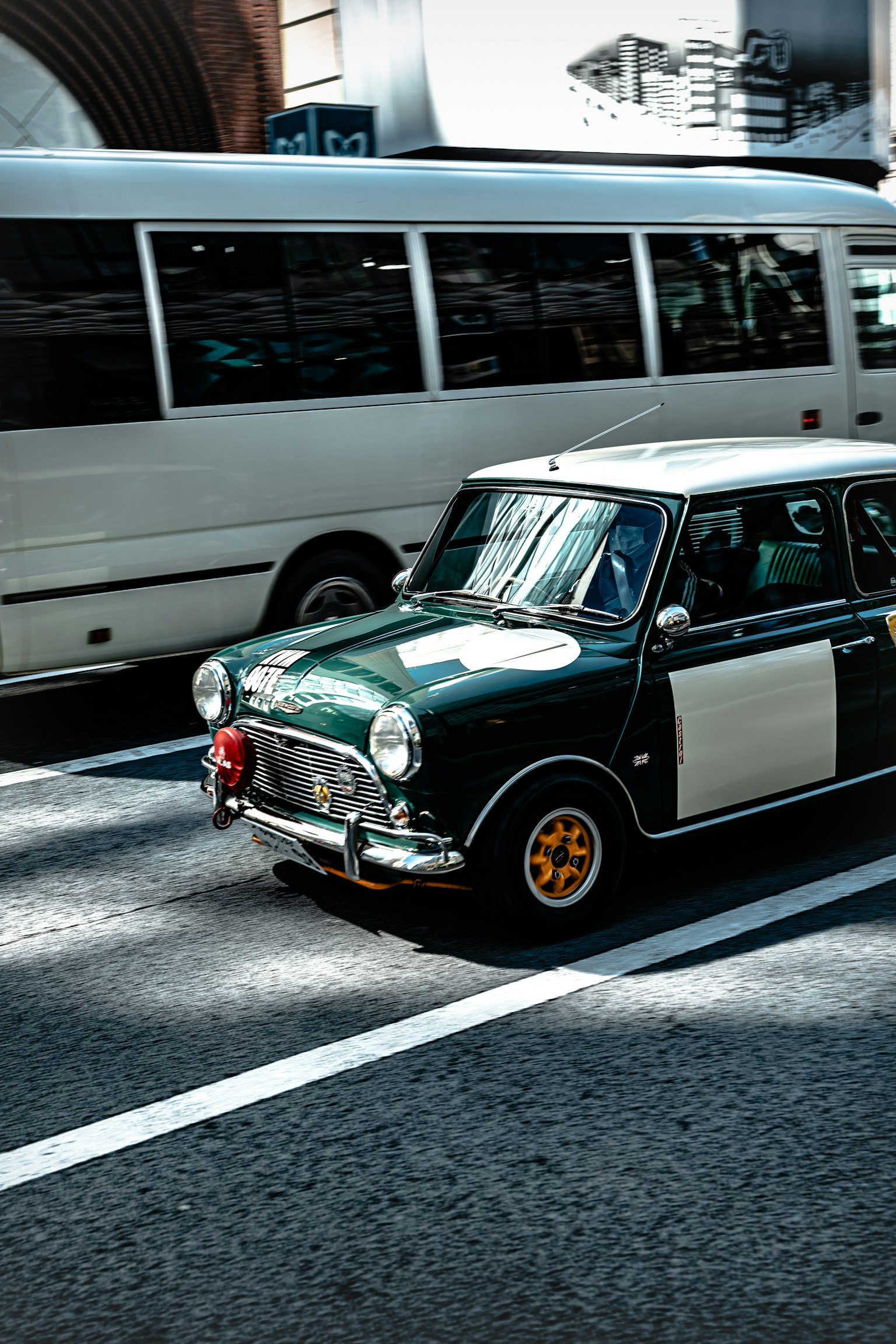 A green and white Mini Cooper driving in the city