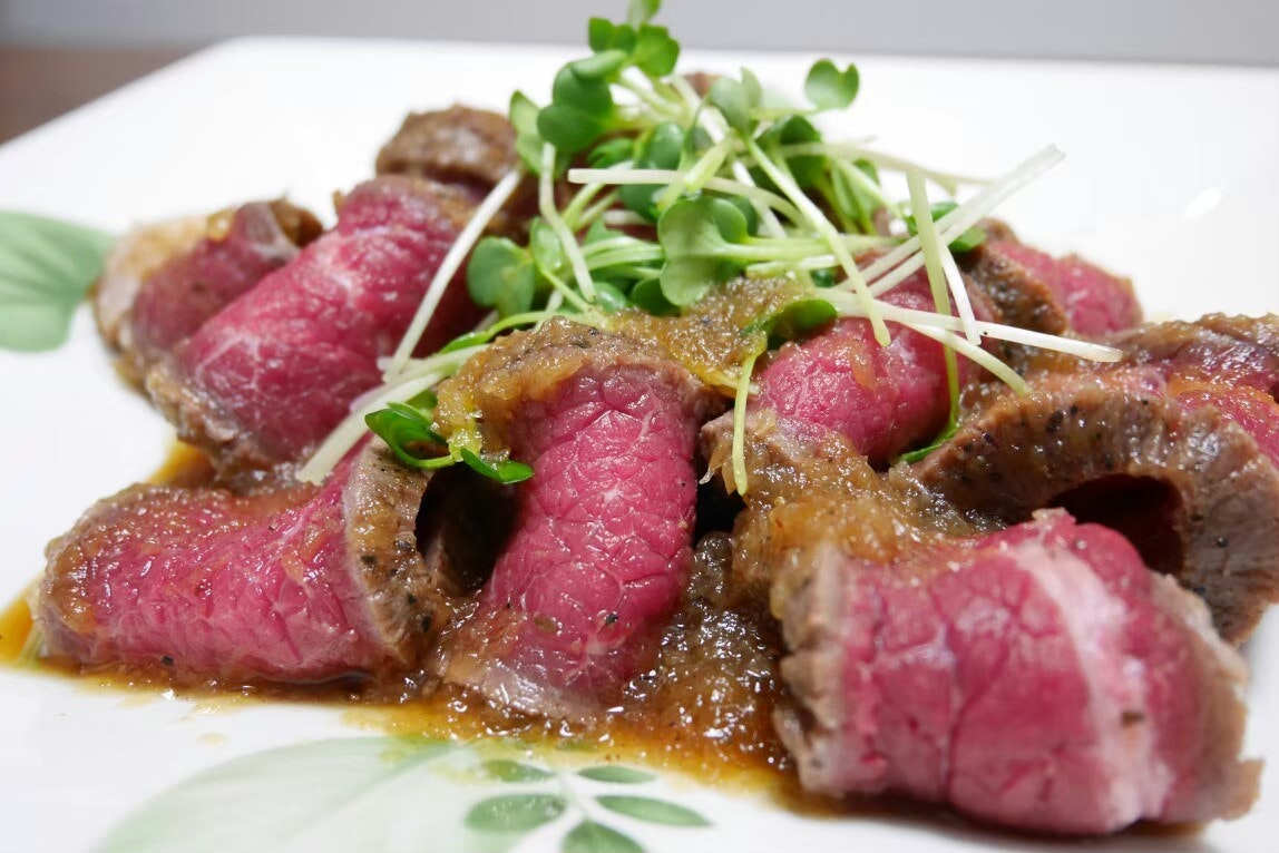 烤牛肉片配粉红色中心与酱汁，上面点缀芽苗