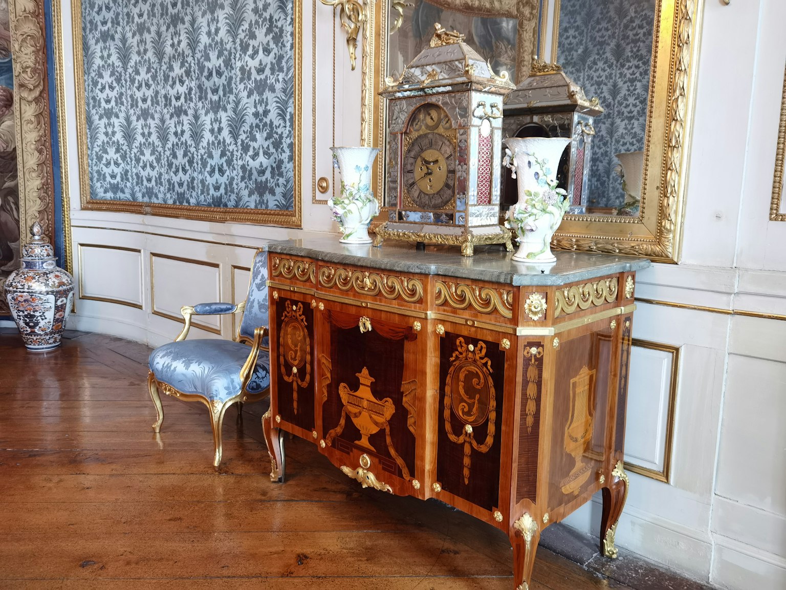 Un angolo di una stanza con un mobile in legno decorato e un orologio antico
