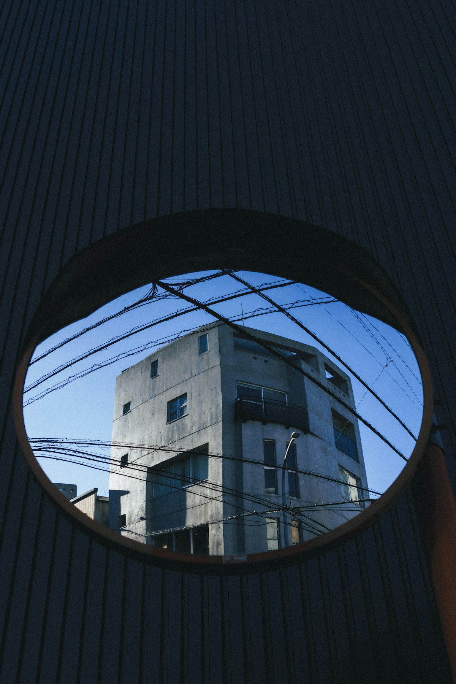 Reflejo de un edificio y cielo azul a través de una ventana redonda