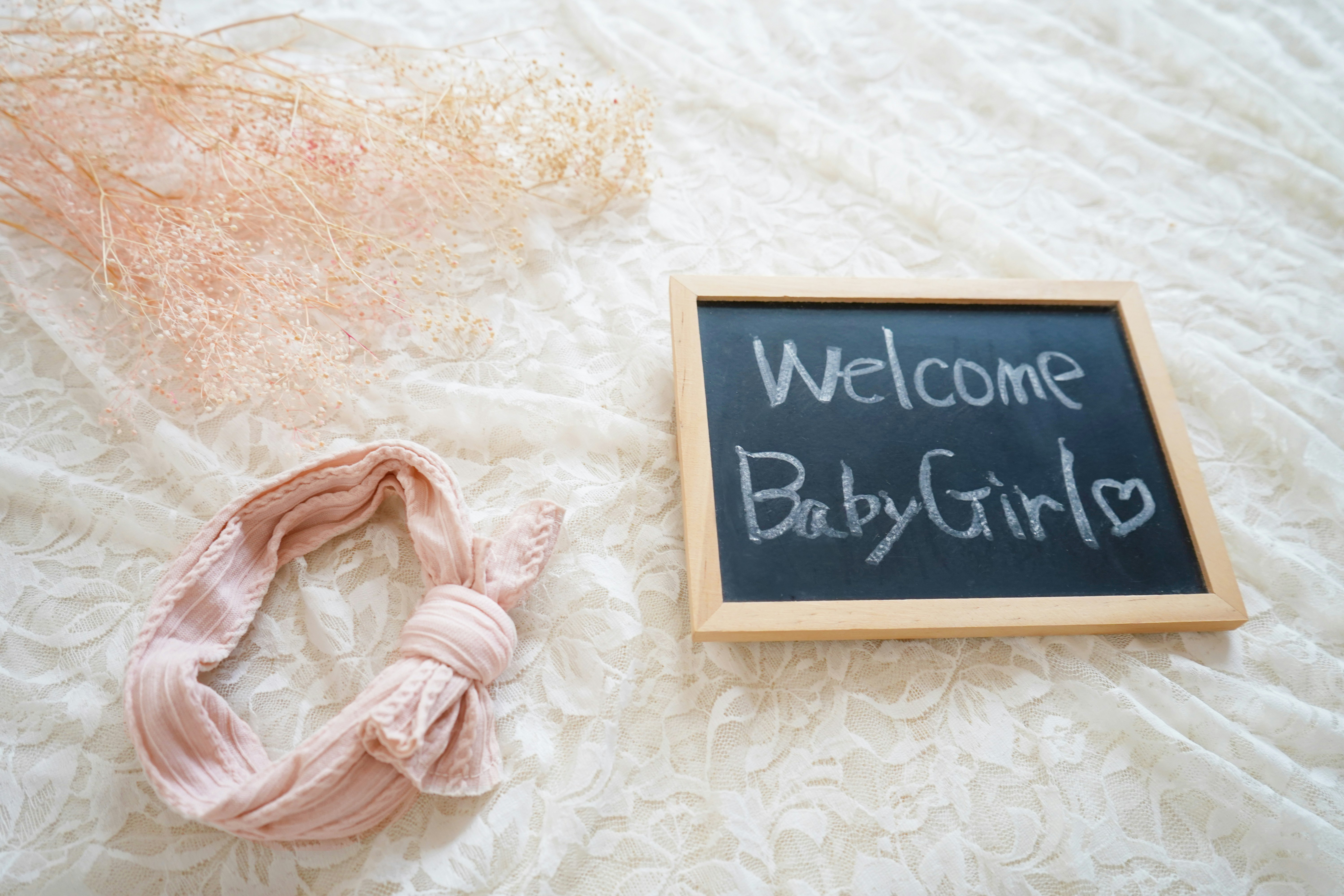 ベビーピンクのリースと「Welcome Baby Girls」の黒板サイン