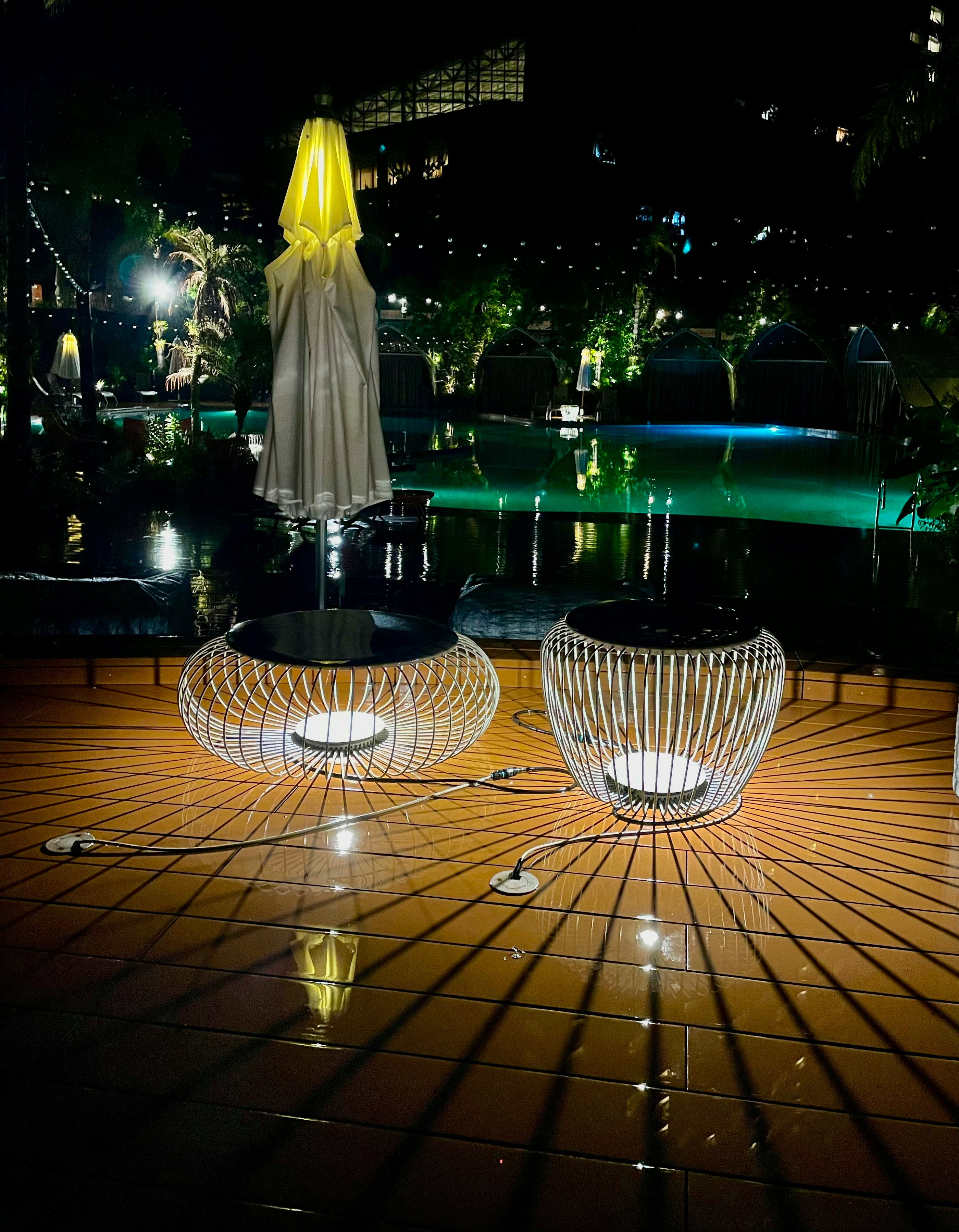 escena nocturna al aire libre junto al agua con decoraciones luminosas y un adorno blanco tipo velo