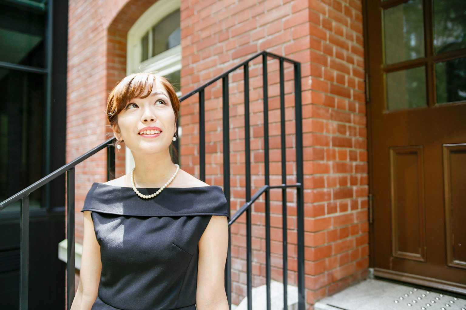 穿着黑色裙子的女人在红砖建筑前微笑