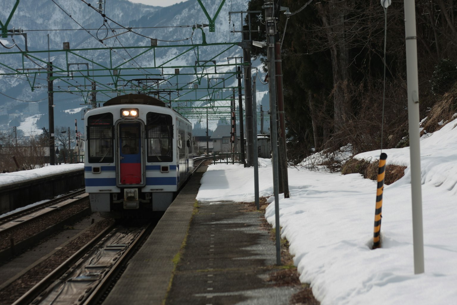 Treno in arrivo in una stazione innevata circondata da montagne