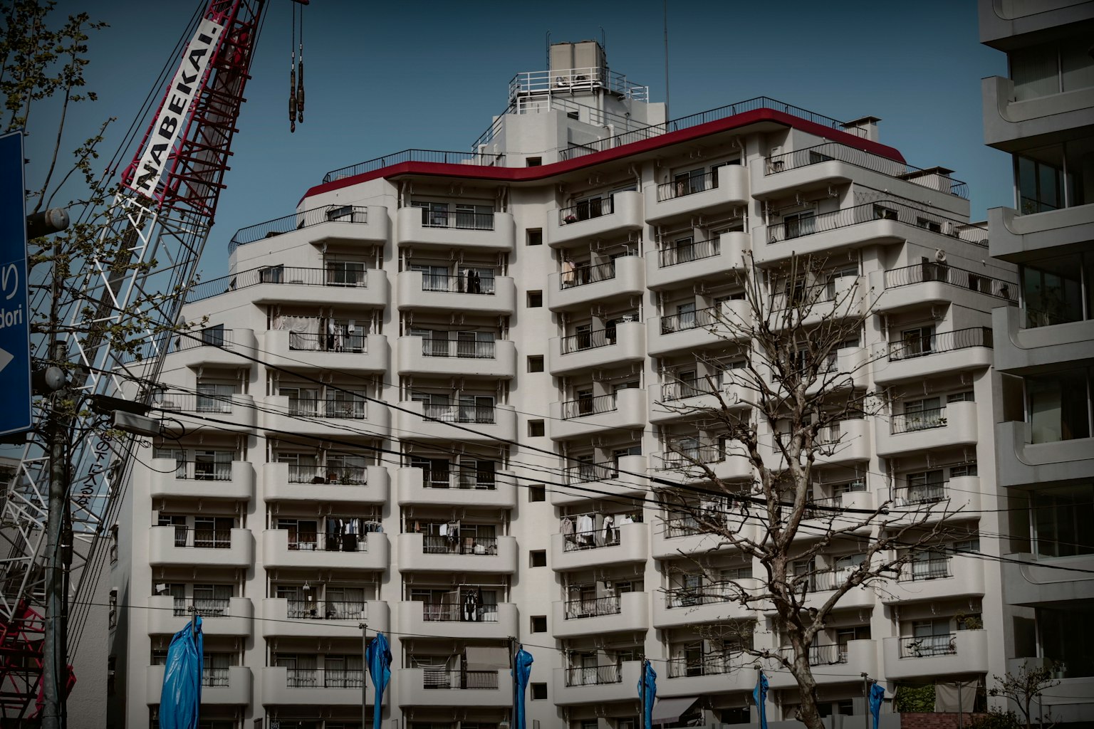 建筑外观为白色，红色屋顶，拥有众多窗户。周围元素包括起重机和树木。