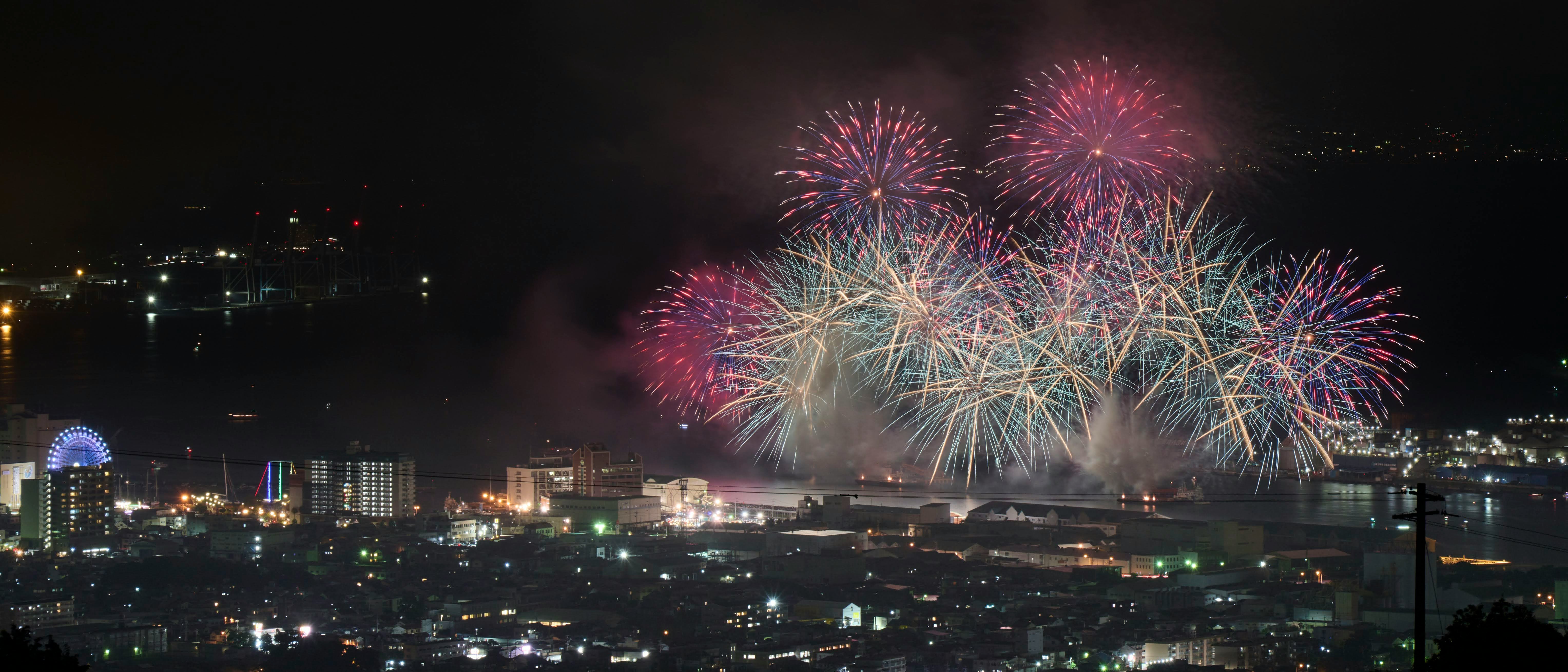 夜の港に広がる花火と街の灯り