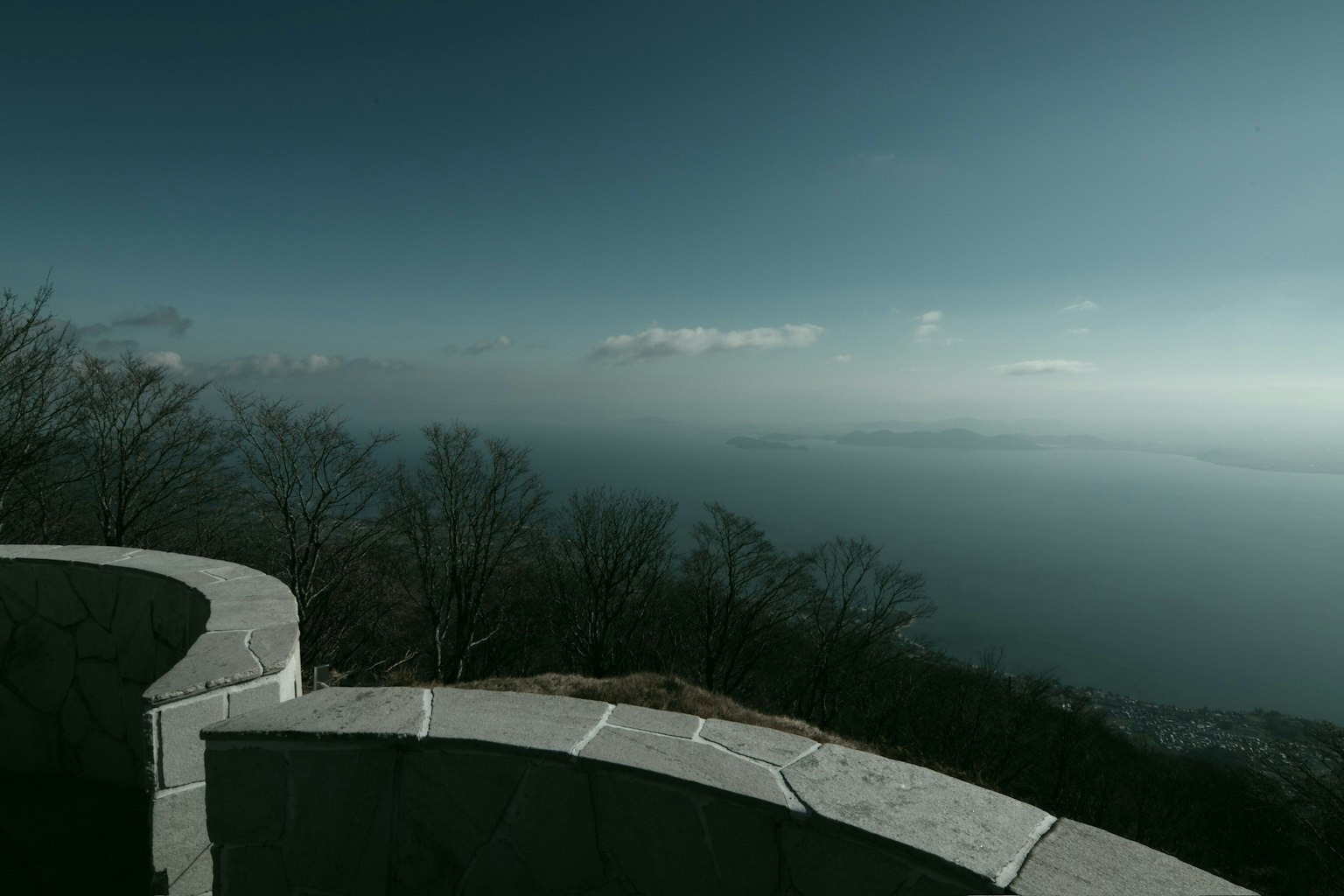 Aussicht von einem Berggipfel auf ein blaues Meer und einen bewölkten Himmel