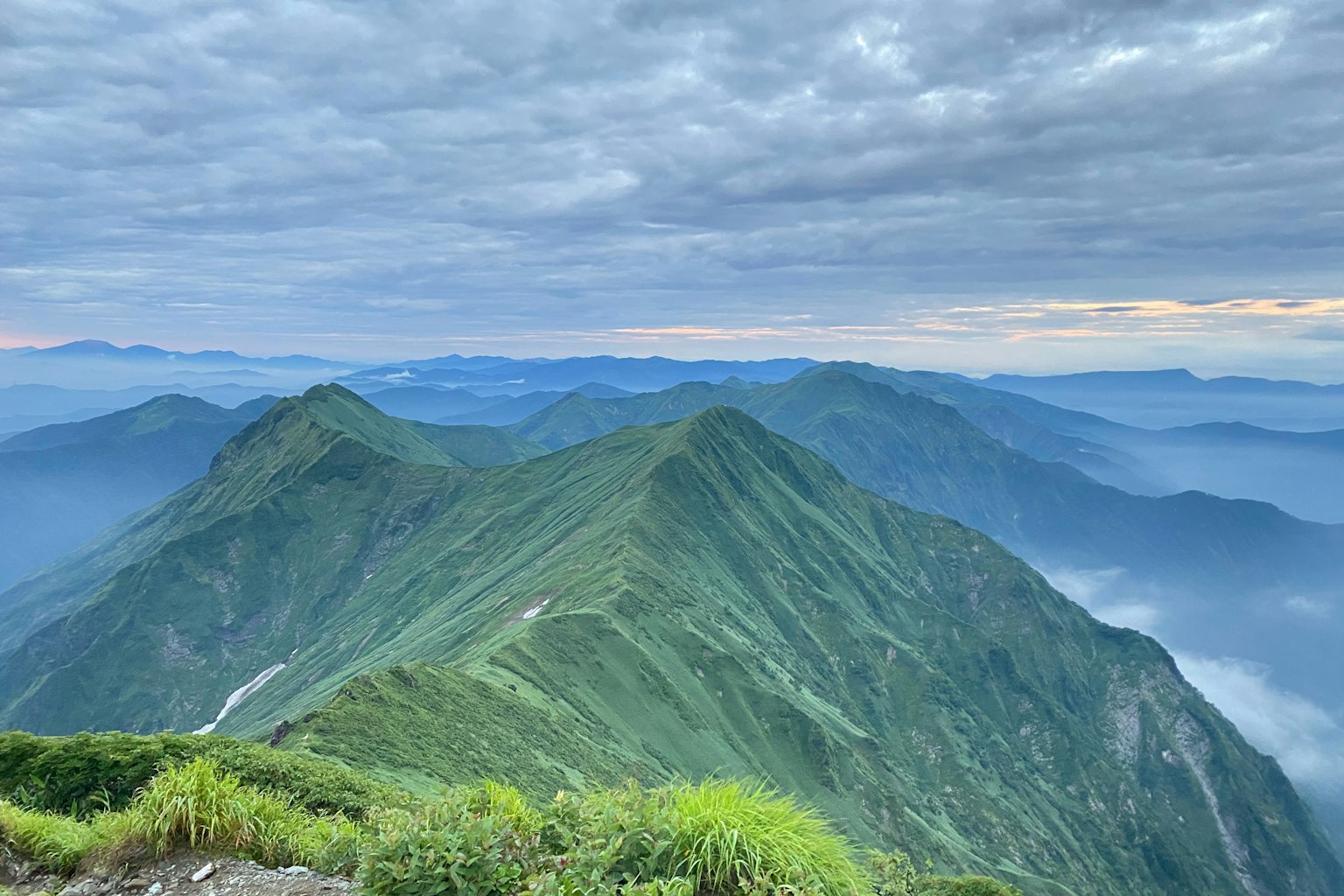 Panoramic view of green mountains with a cloudy sky
