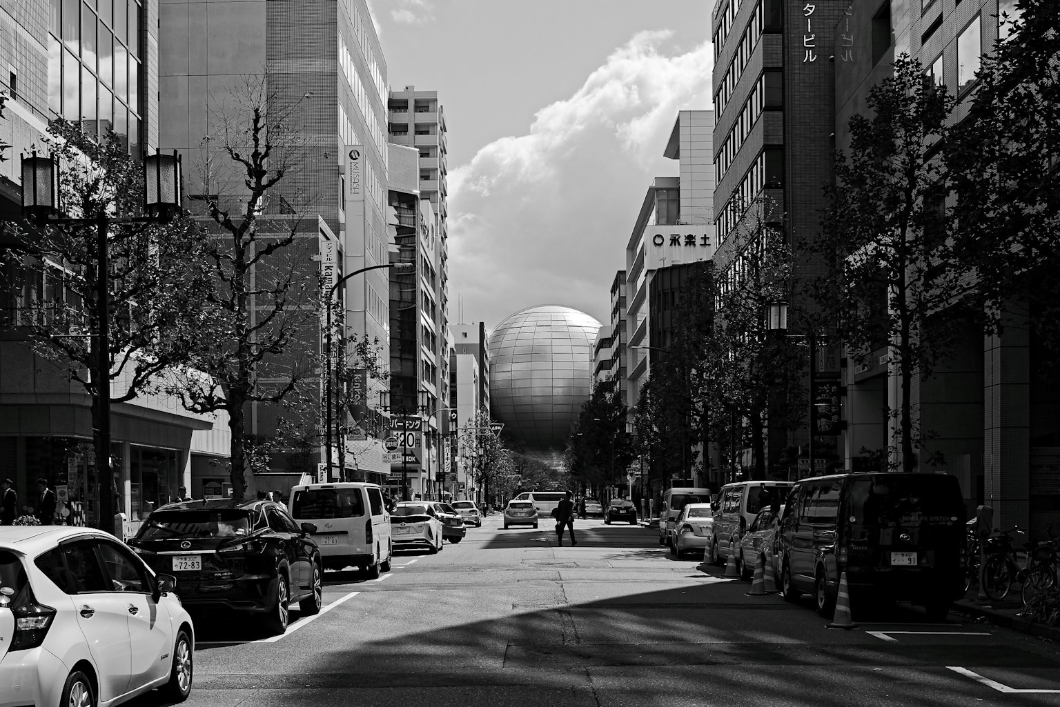 Escena urbana en blanco y negro con una gran estructura esférica
