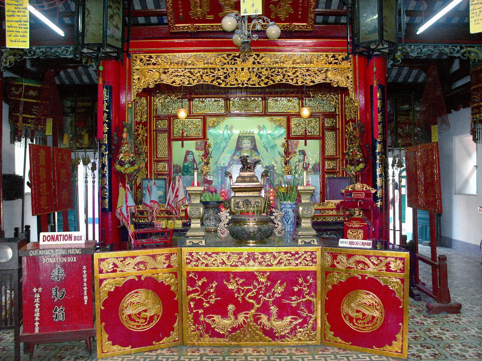 Intricately decorated altar in a temple featuring vibrant red and gold colors with various sculptures and figures