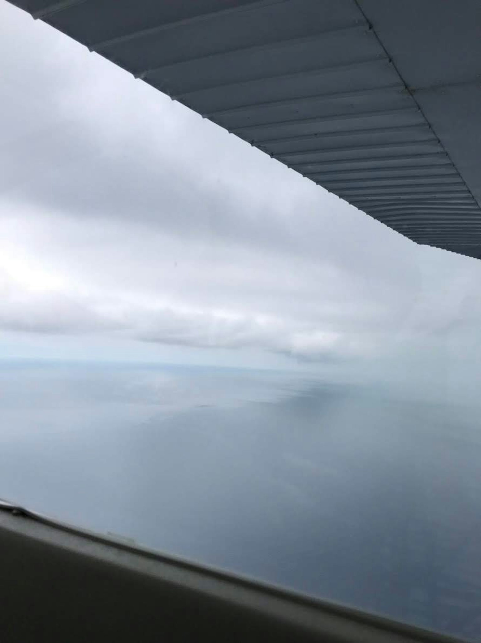 Vue océanique nuageuse avec une partie de l'aile d'un avion