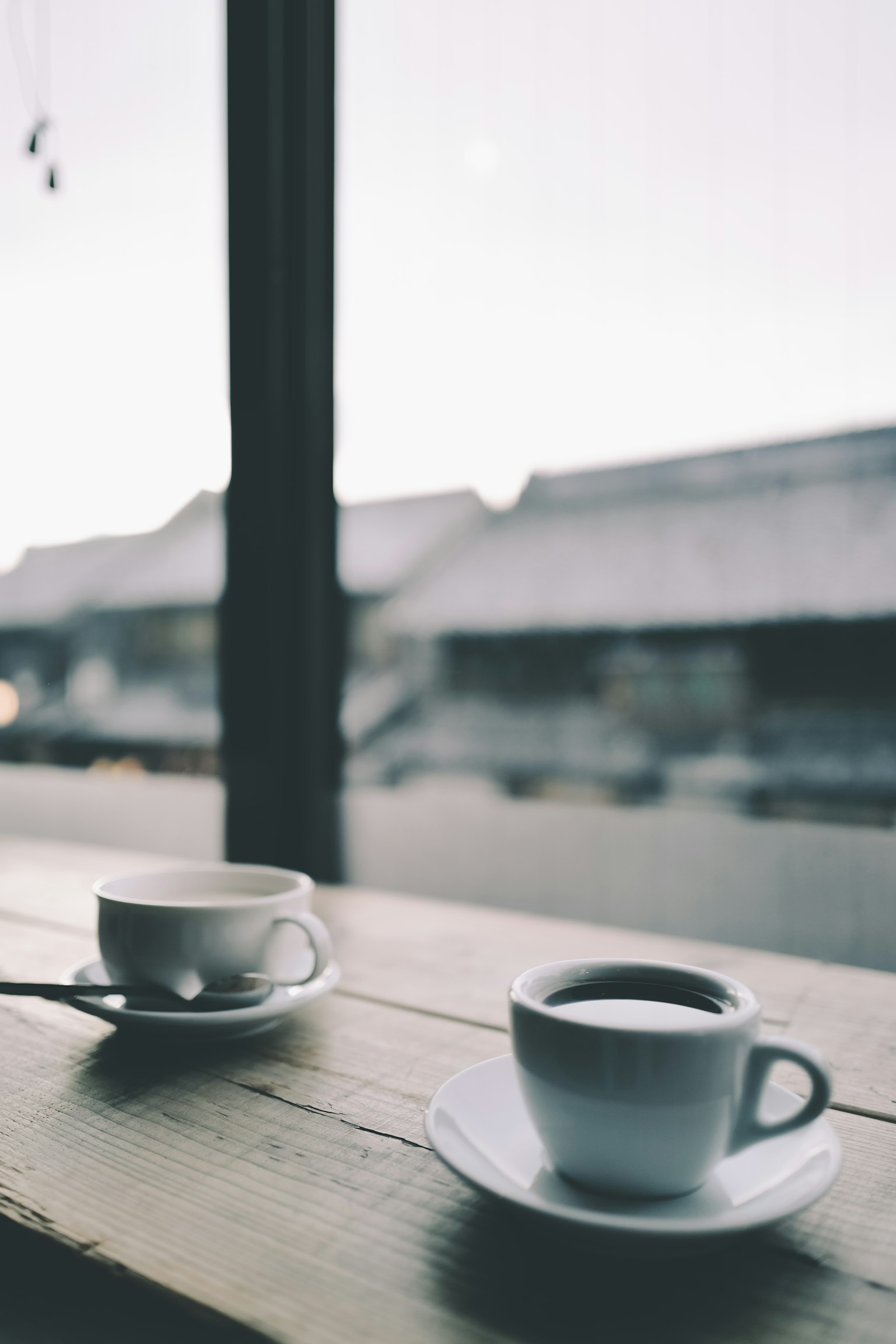 Due tazze di caffè su un tavolo di legno vicino a una finestra