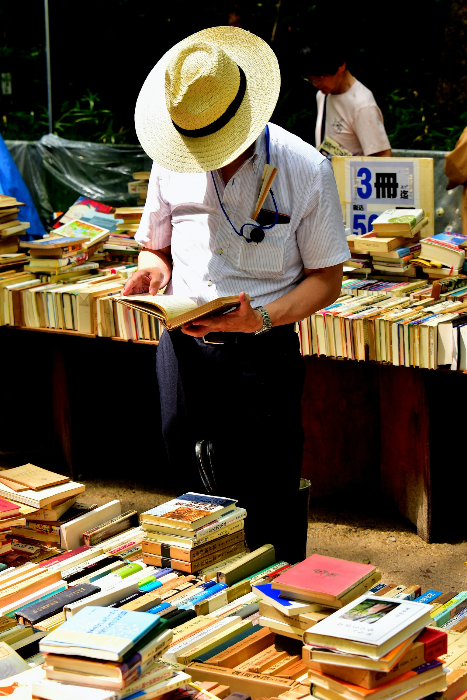 戴著帽子的男人在書堆中閱讀書籍專注於書本