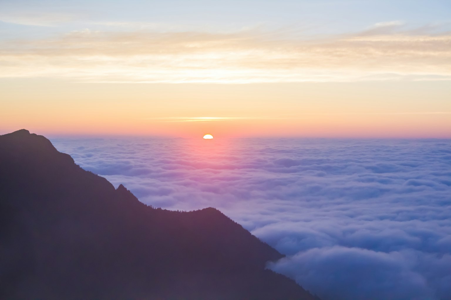 Matahari terbit di atas lautan awan dengan warna langit lembut