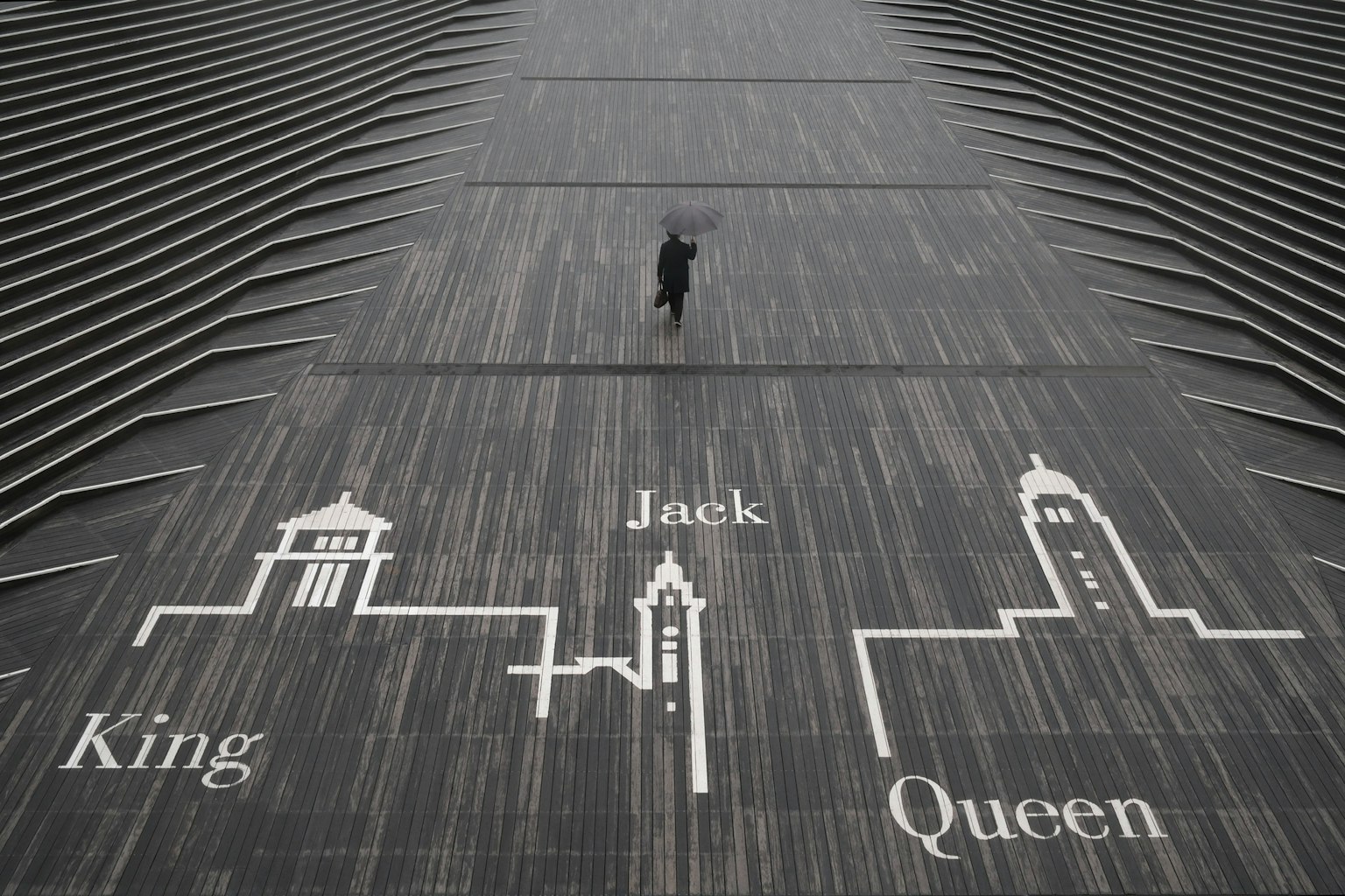 一个人站在一个木地板上，上面有国王、杰克和女王的符号