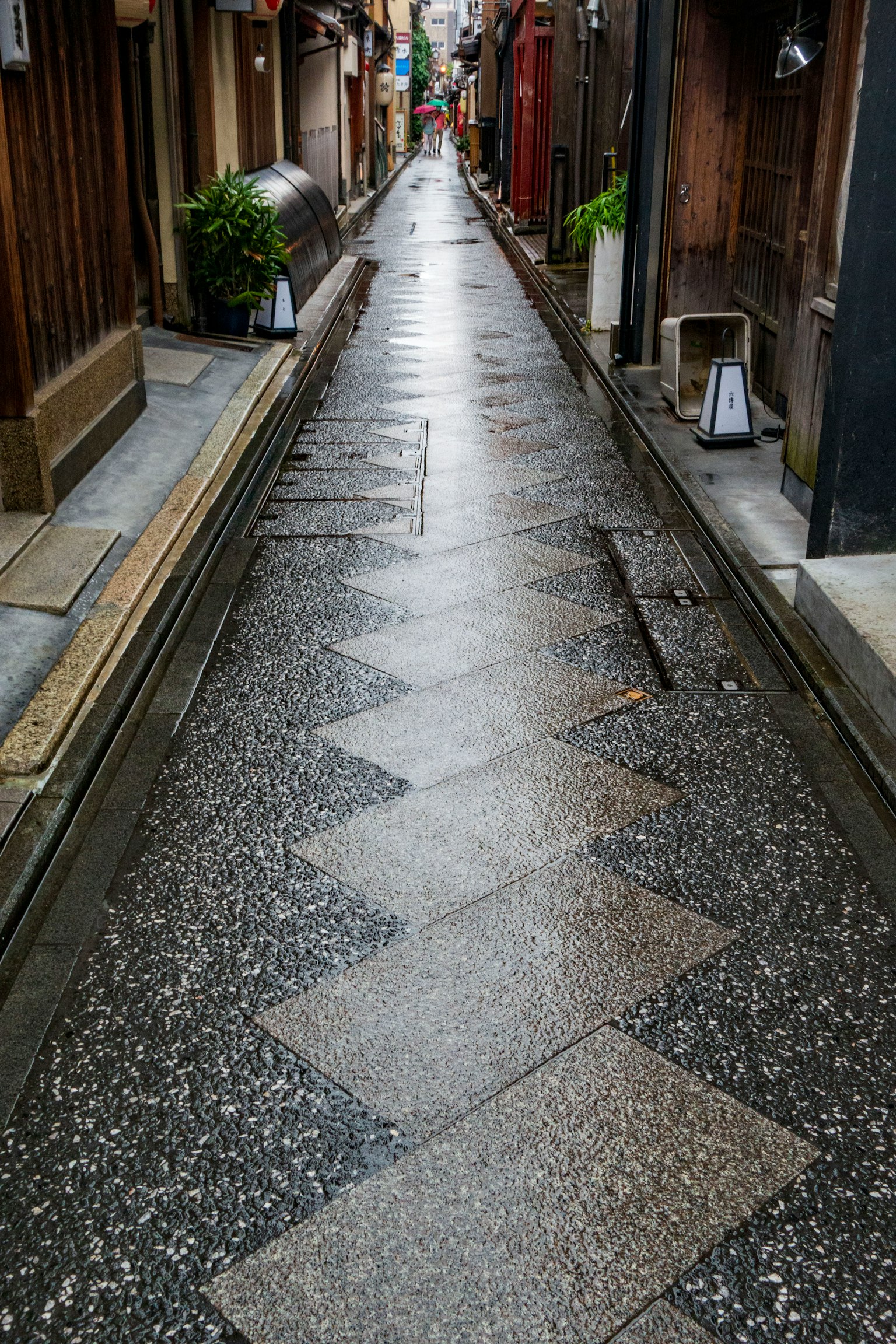 Narrow wet alley with patterned stone pavement and traditional buildings