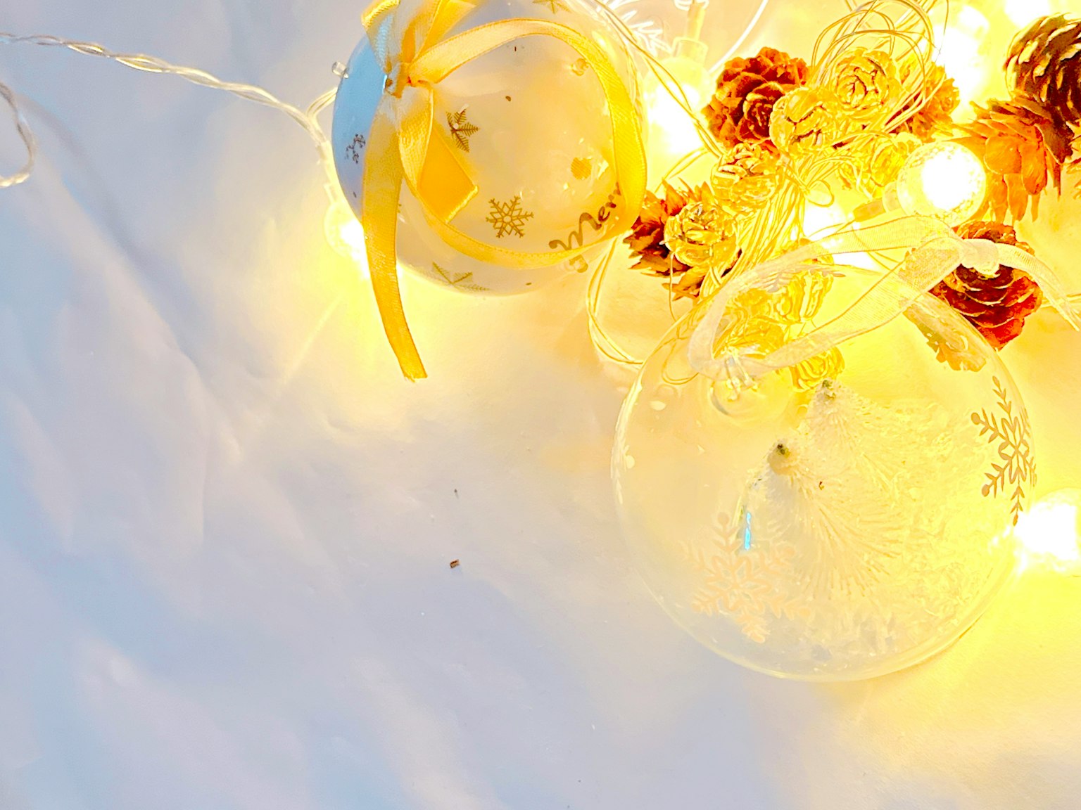 Christmas ornaments and pine cones on a white background with warm lights